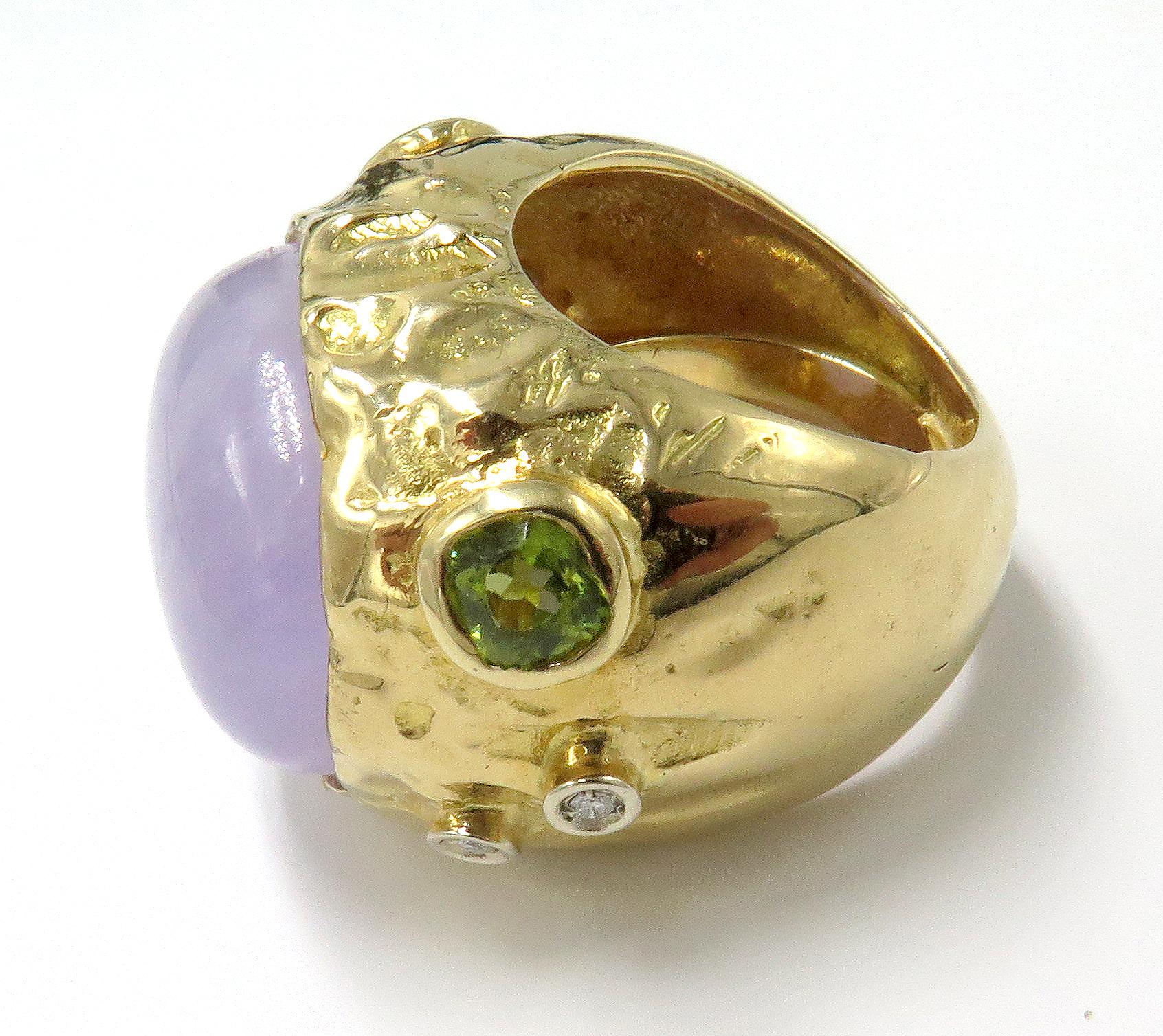 This, is a gorgeous and beautiful 18k ring that features a beautiful lavender jade in the center of the ring. This, ring is crafted in 18K yellow gold with a combination of a polished and hammered finish. On the sides of the ring there is an array
