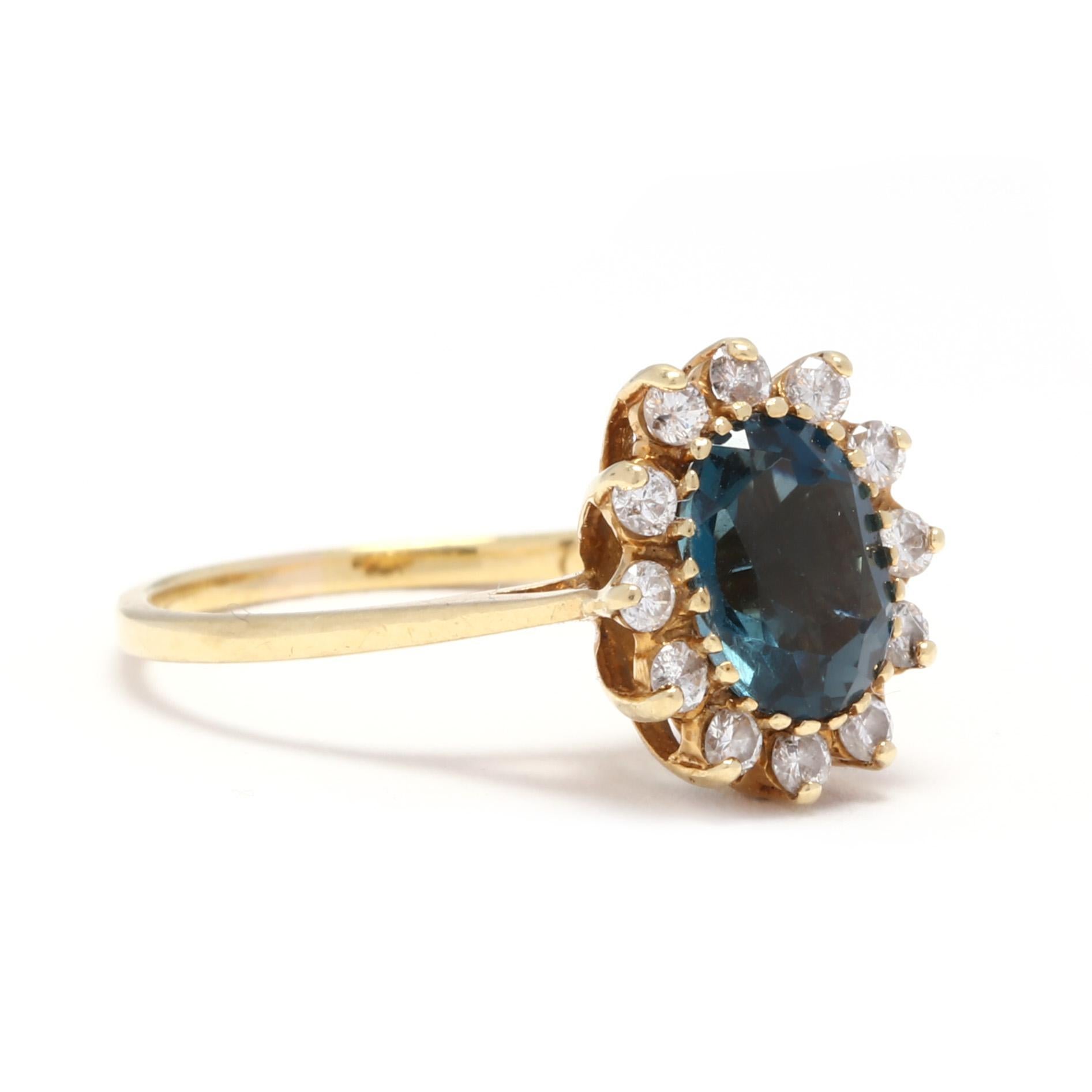 An 18 karat yellow gold, London blue topaz and diamond ring. This ring features a prong set, oval cut London blue topaz surrounded by a halo of full cut round diamonds weighing approximately .18 total carats and with a thin, slightly tapered