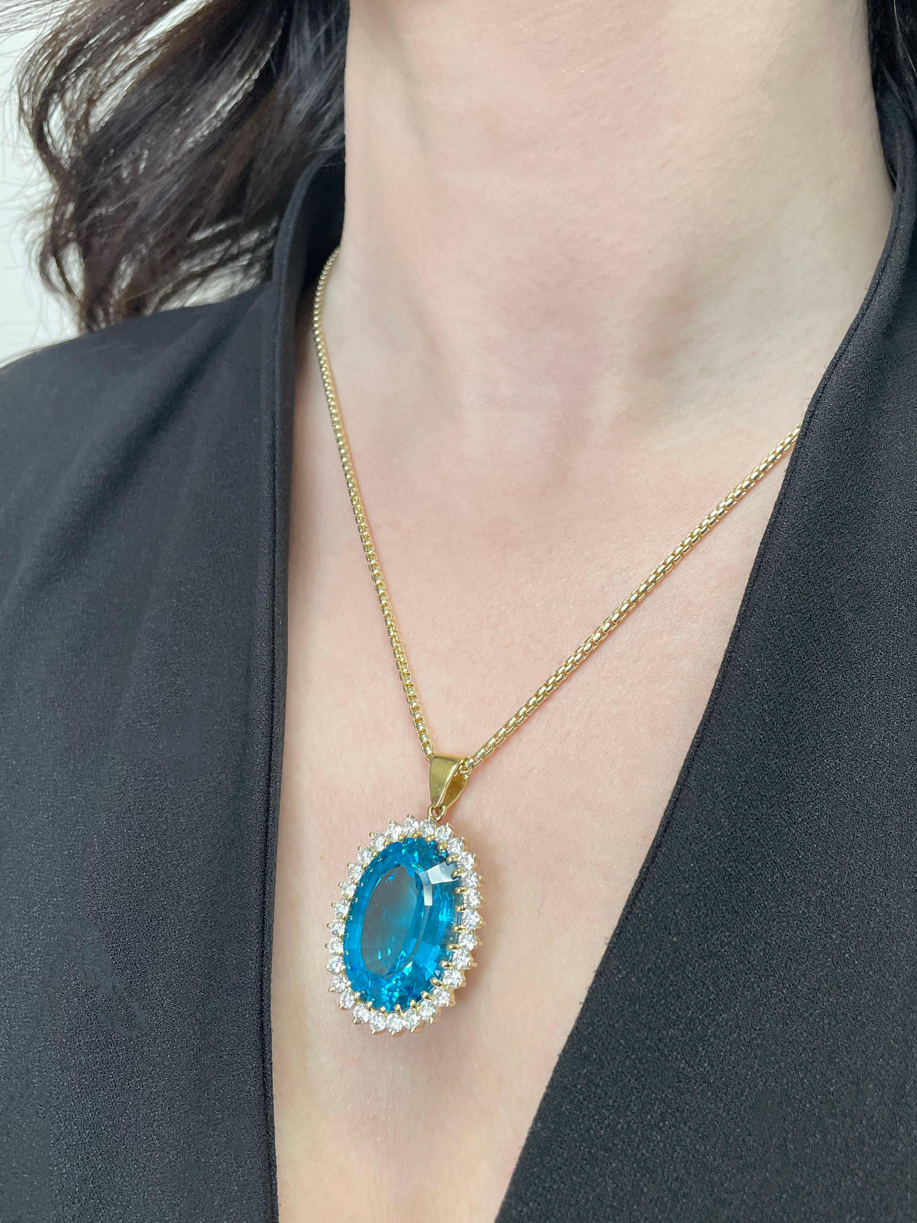 Pendente usato in oro giallo 18K con un topazio blu di Londra di forma ovale di circa 28mmx19,40mm.  Il topazio è circondato da 28 diamanti rotondi a taglio brillante per un peso totale di circa 3,00 carati (colore E/F, purezza VS). Il ciondolo