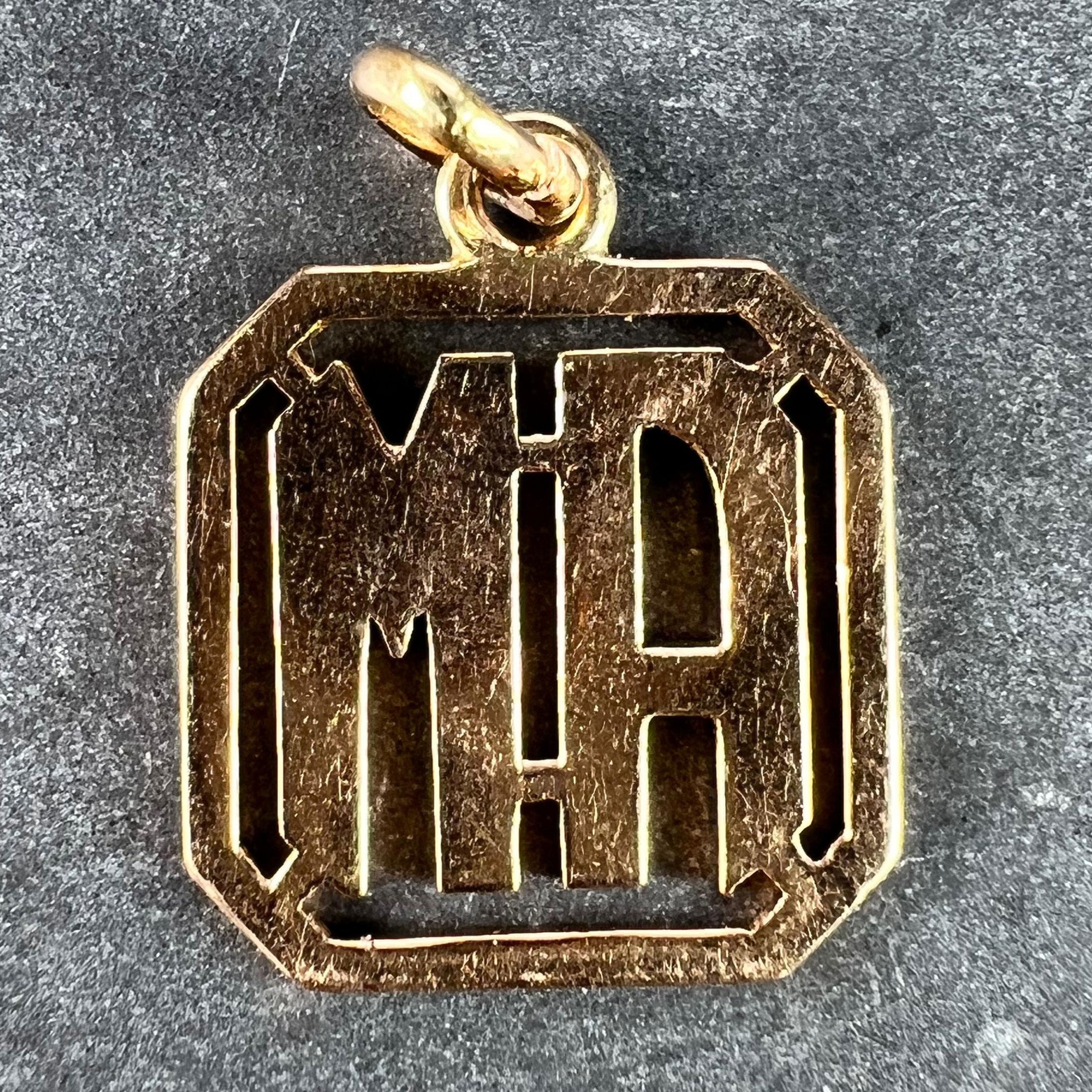 An 18 karat (18K) yellow gold charm pendant designed as a pierced square monogram of the initials MA or AM. Unmarked but tested for 18 karat gold.

Dimensions: 1.7 x 1.4 x 0.1 cm (not including jump ring)
Weight: 1.82 grams 
(Chain not included)