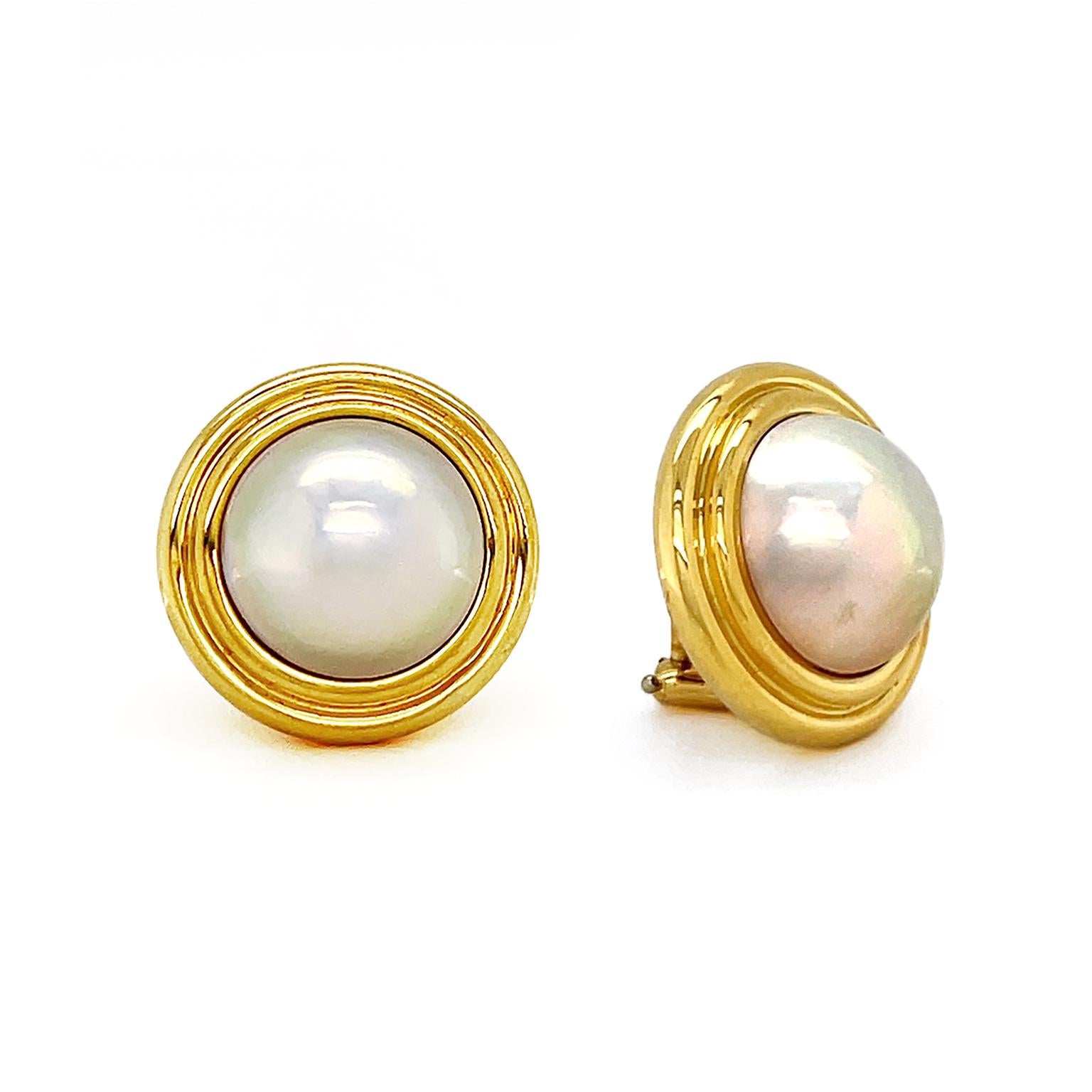 Delicate opalescent hues lift from the bodies of mabe pearls for these earrings. Half orbs of the pearls are accented by the vibrant glow from a pair of 18k yellow gold trimming. The total weight is 2 carats of mabe pearl. Clip-backs attach the