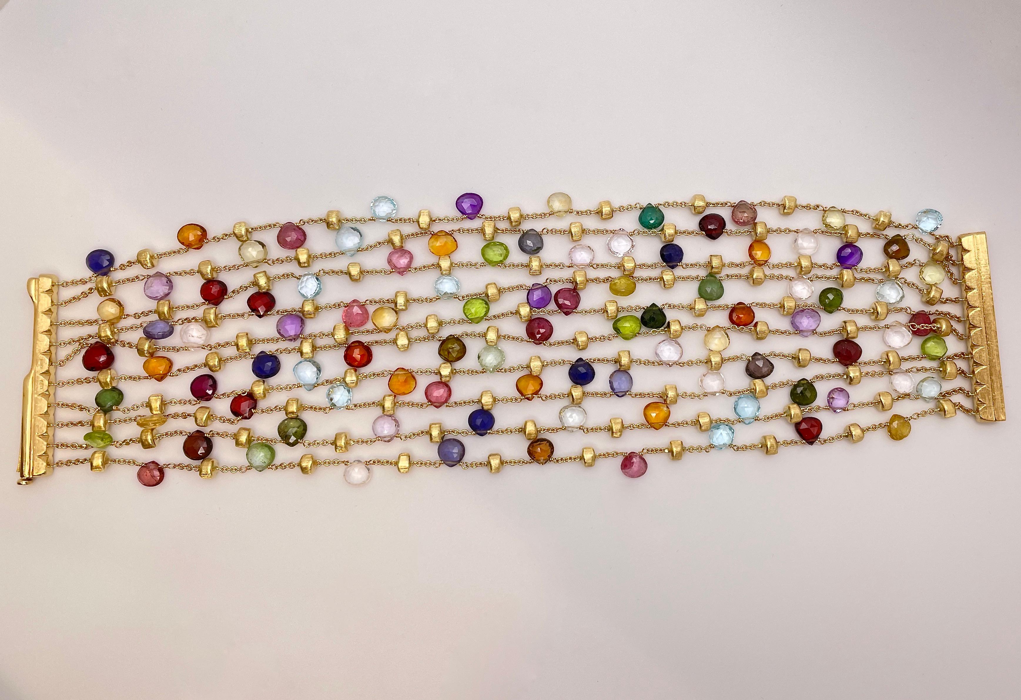 An incredible 18K yellow gold Marco Bicego multi-color stone strand bracelet. The wide range of colors emanating from these beautiful gems creates an entrancing and heavenly display. With a length of 8 inches and 10 different strands (1.50 inches