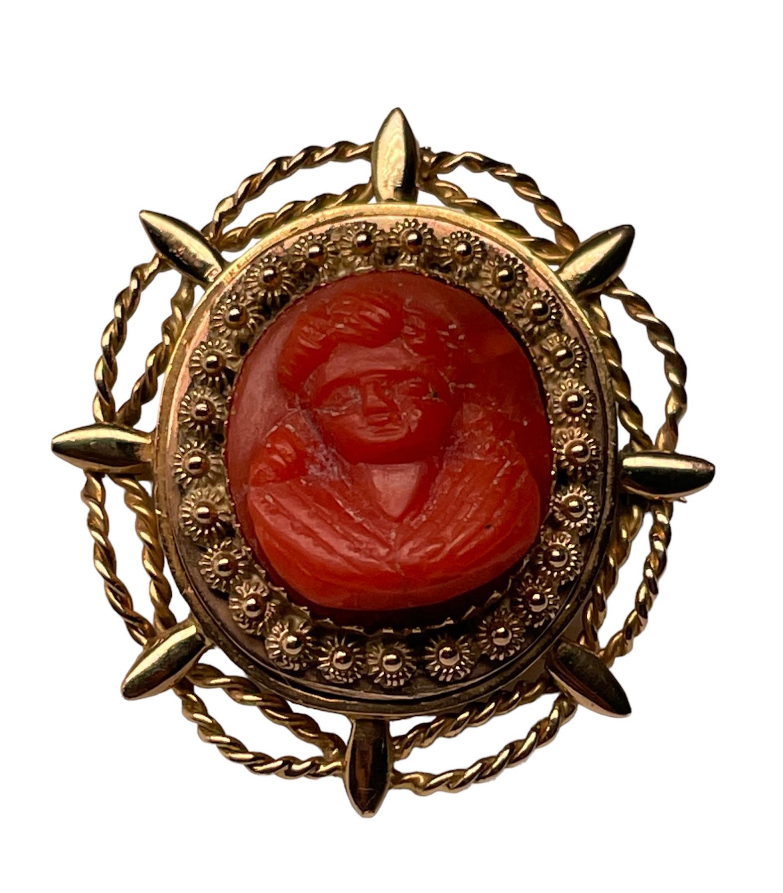 This is an 18k Yellow gold Mediterranean coral cameo brooch/pendant. The high relief hand carved round coral cameo depicts the portrait of a young girl. It is mounted in a gold round frame that is decorated with floral cannetilles. A steering wheel