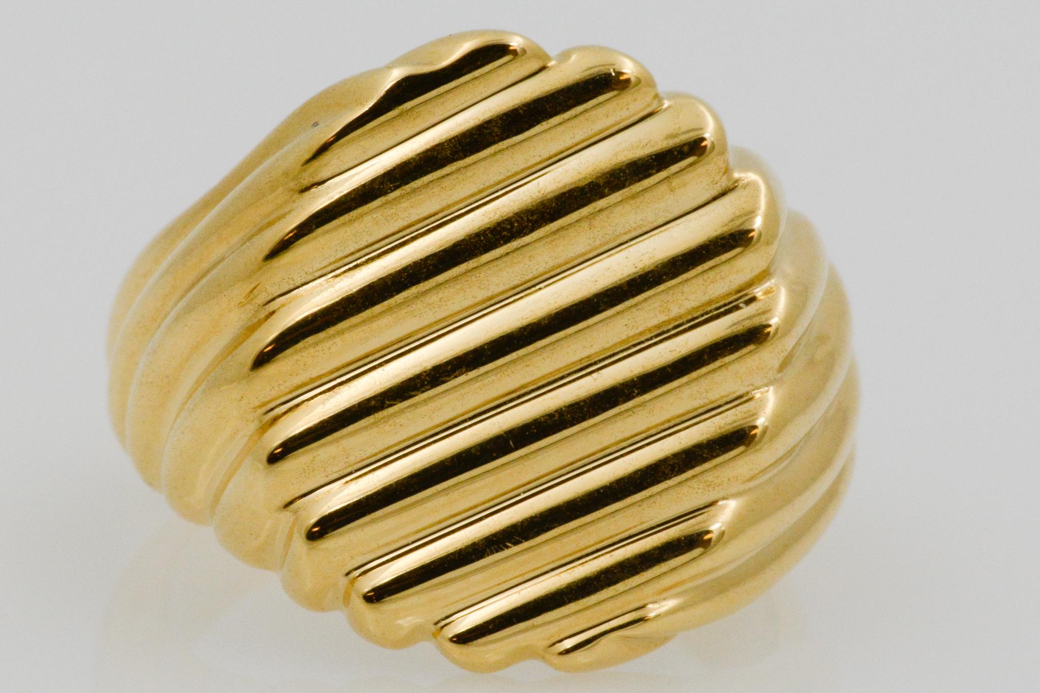 This 18k yellow gold men's ring has a flat face with a ridged design in a size nine. The ridges swirls around the edges and has a single design on the front. 

