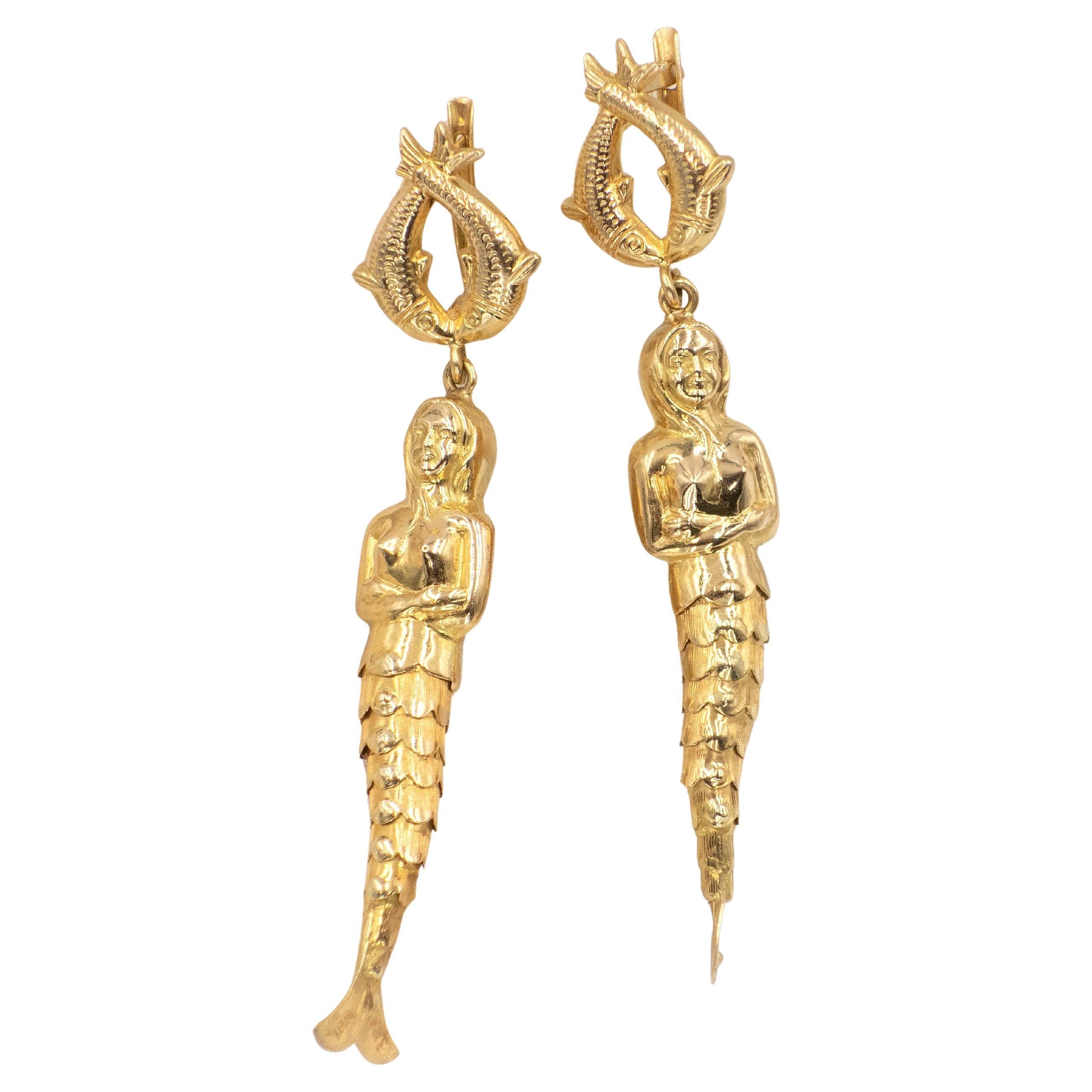 Fantaisistes et sculpturales, ces boucles d'oreilles des années 1960 sont réalisées en or jaune 18 carats massif. Chaque boucle d'oreille représente une sirène détaillée avec une queue texturée et écaillée, suspendue à un motif supérieur composé de