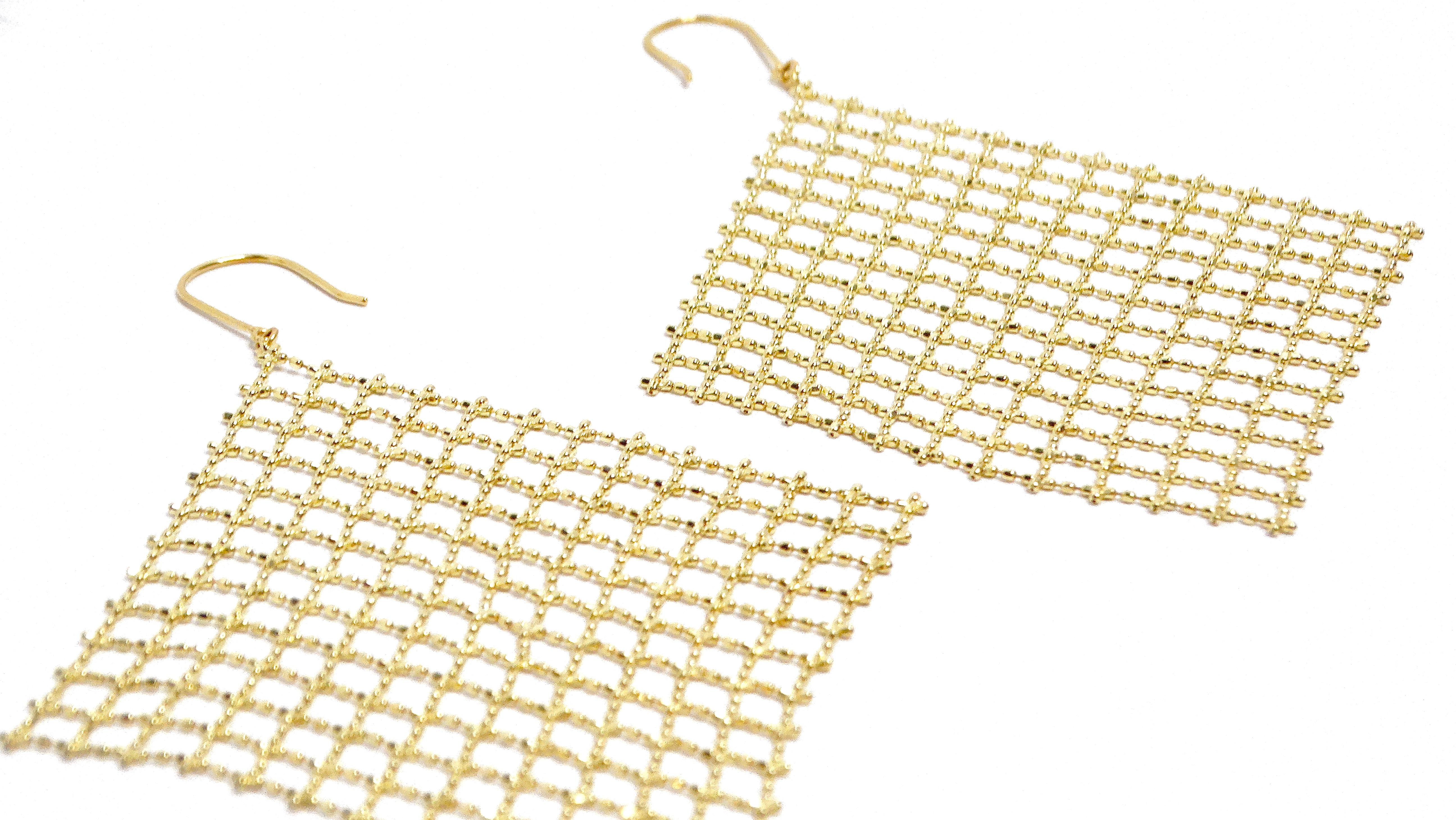 The 18k Yellow Gold Mesh Wire Chandelier Earrings are a stunning example of intricate craftsmanship and luxurious design. Each earring dangles gracefully, with a captivating lattice pattern that adds texture, depth, and movement. These earrings are