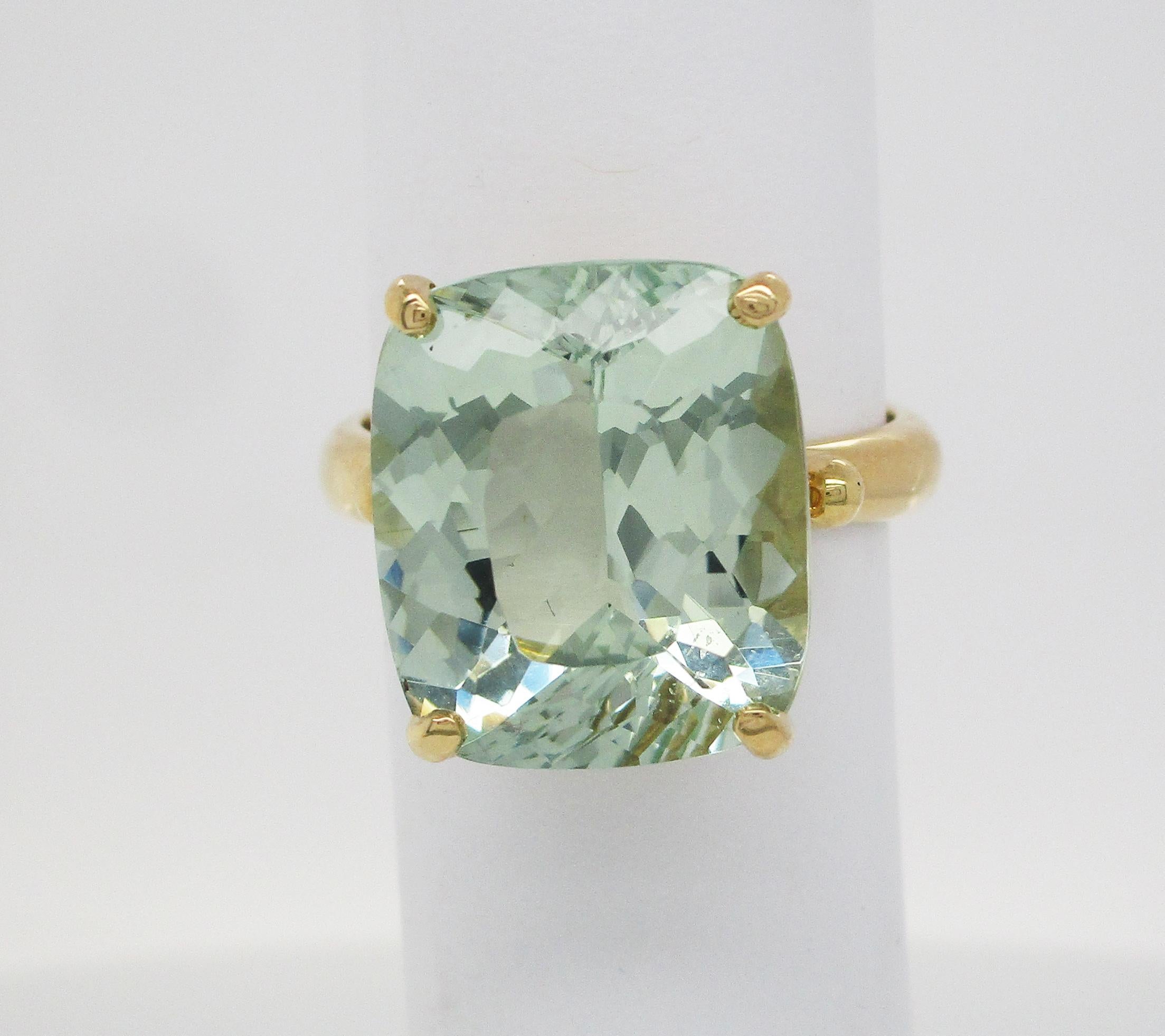 This is a beautiful ring in 18k yellow gold with a delightful mint green beryl center stone! The ring itself is an elegant design with under gallery details featuring overlapping curves and negative space. The rich yellow gold is the perfect frame