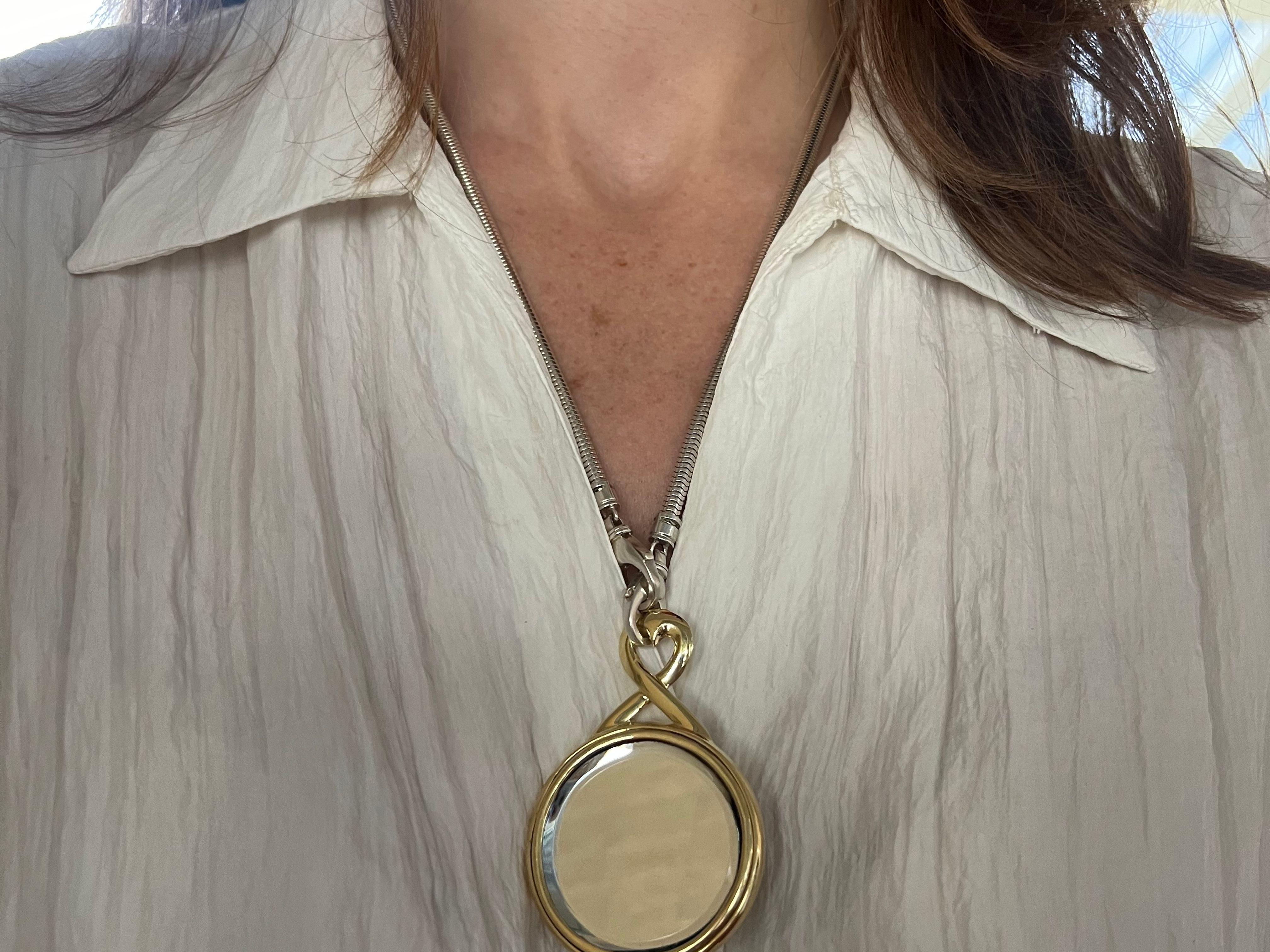 This exquisite 18k yellow gold pendant is a testament to elegance and thoughtful design. Featuring a heart-shaped bale, it combines romantic symbolism with luxurious craftsmanship. The front of the pendant boasts a polished round mirror, reflecting
