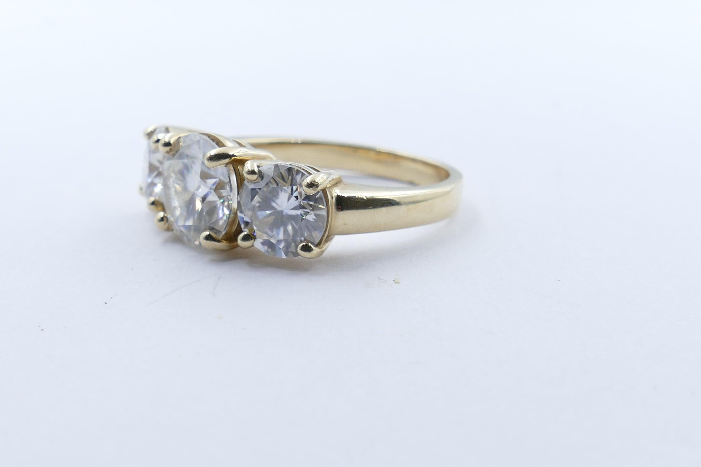 One 2 carat white Moissanite, 8.12 X 8.11 X 4.78,  VS clarity, forms the centrepiece of these beautiful looking Ring, set in 18 karat Yellow Gold.
It is 4 claw set & flanked by 2 other Moissanites , slightly smaller but of similar standard in colour
