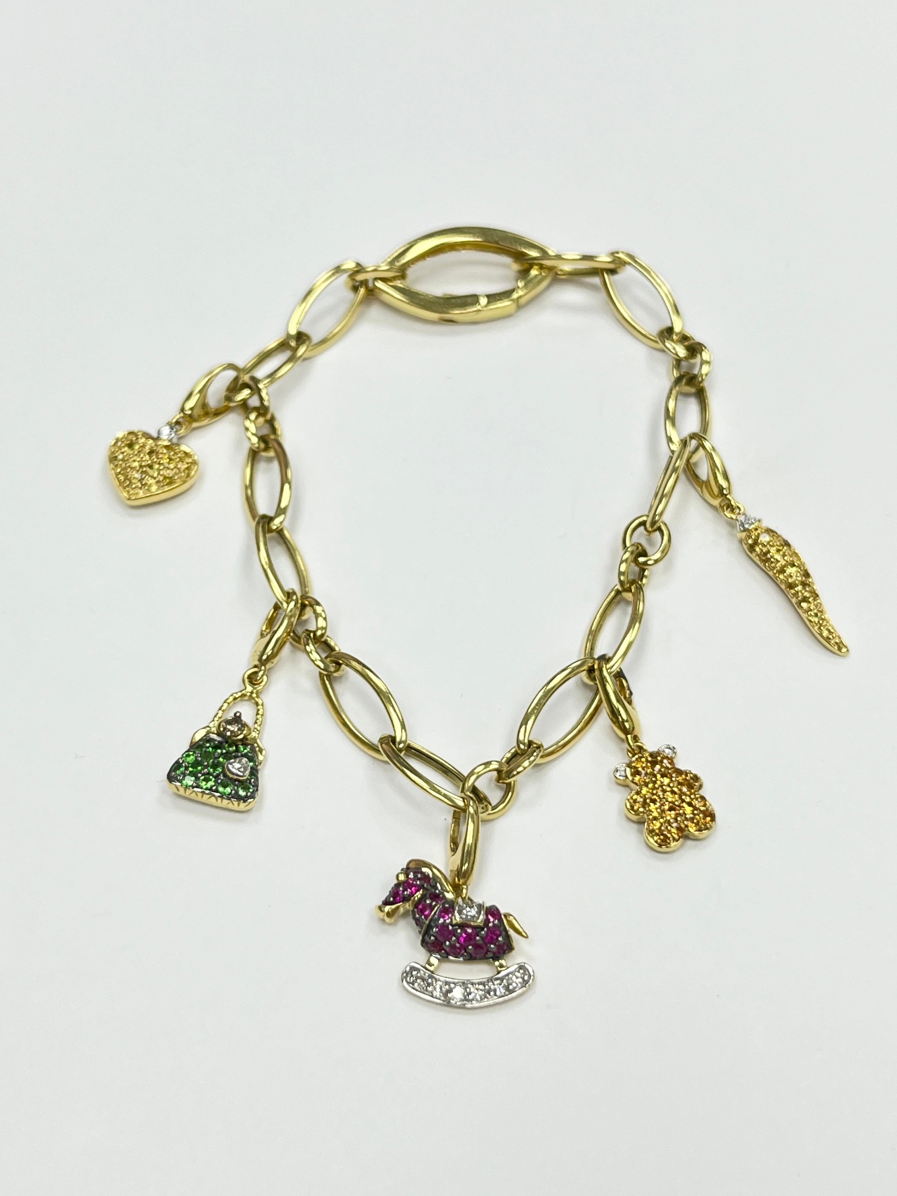 18K yellow gold 5 charms bracelet with yellow sapphire, emerald, ruby and diamond
with 1 heart, 1 purse, 1 rocking horse, 1 Teddy bear, 1 lucky horn charm, they are detachable
Weight: 16.2 g 
Marked 750 and Italian hallmark
Length: 7.5 inches