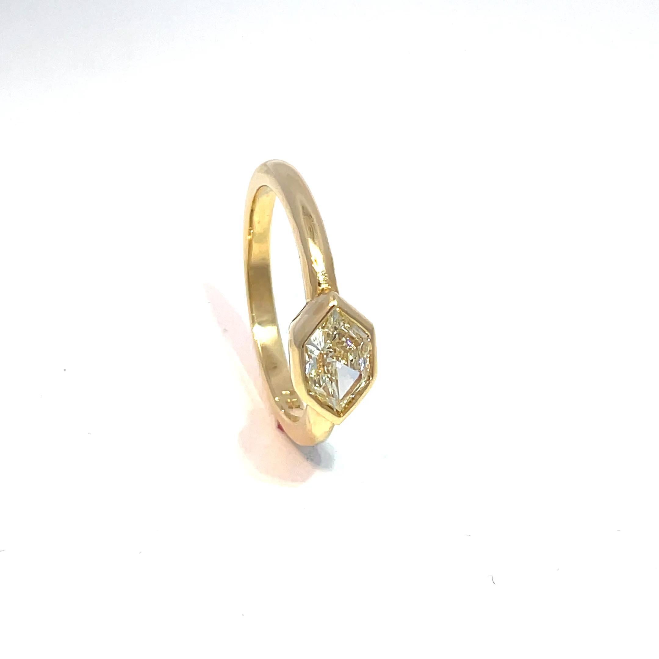 This ring showcases a mixed-cut white diamond set in a sleek bezel. Crafted from 18k yellow gold, the design is modern and minimalist. The diamond's brilliance is highlighted by the clean lines of the setting, offering a contemporary