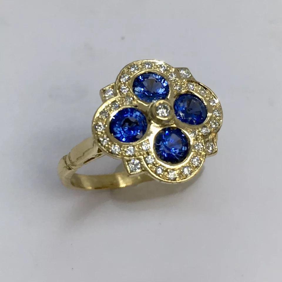 Elevate your jewelry collection with this stunning 18K yellow gold cocktail ring. The beautiful blue sapphire stone serves as the centerpiece of this ring, surrounded by a cluster of 36 clean and clear diamonds. The oval-shaped main stone is set in
