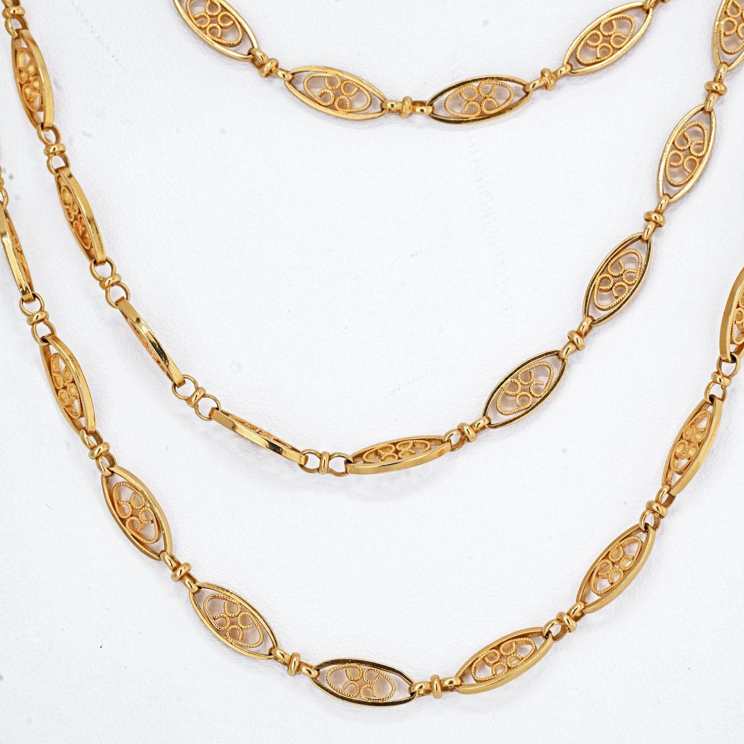 This antique gold long chain necklace is composed of rounded navette-form links with interior wire work motifs joined by circular trace link chain. Its flexibility and delicate construction make it light and versatile, easy to pair with