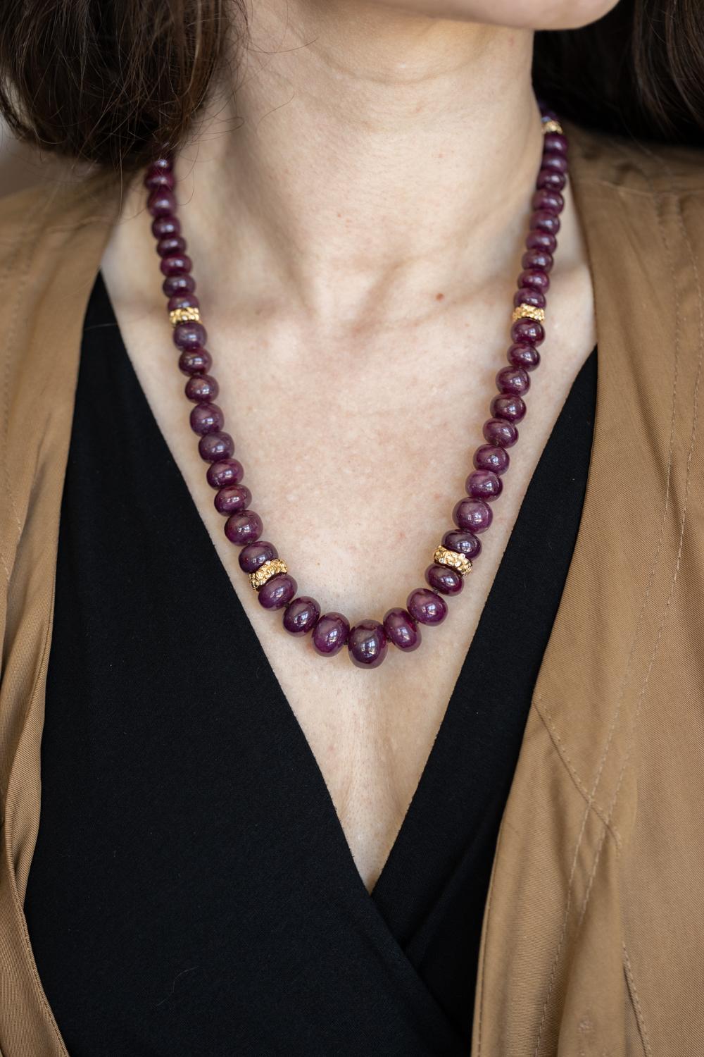 Questa squisita collana di rubini e diamanti emana lusso e raffinatezza. Presenta perle di rubino radioso e distanziatori floreali in oro giallo 18 carati con la giusta quantità di diamanti scintillanti. Le rondelle d'oro intagliate a mano con un
