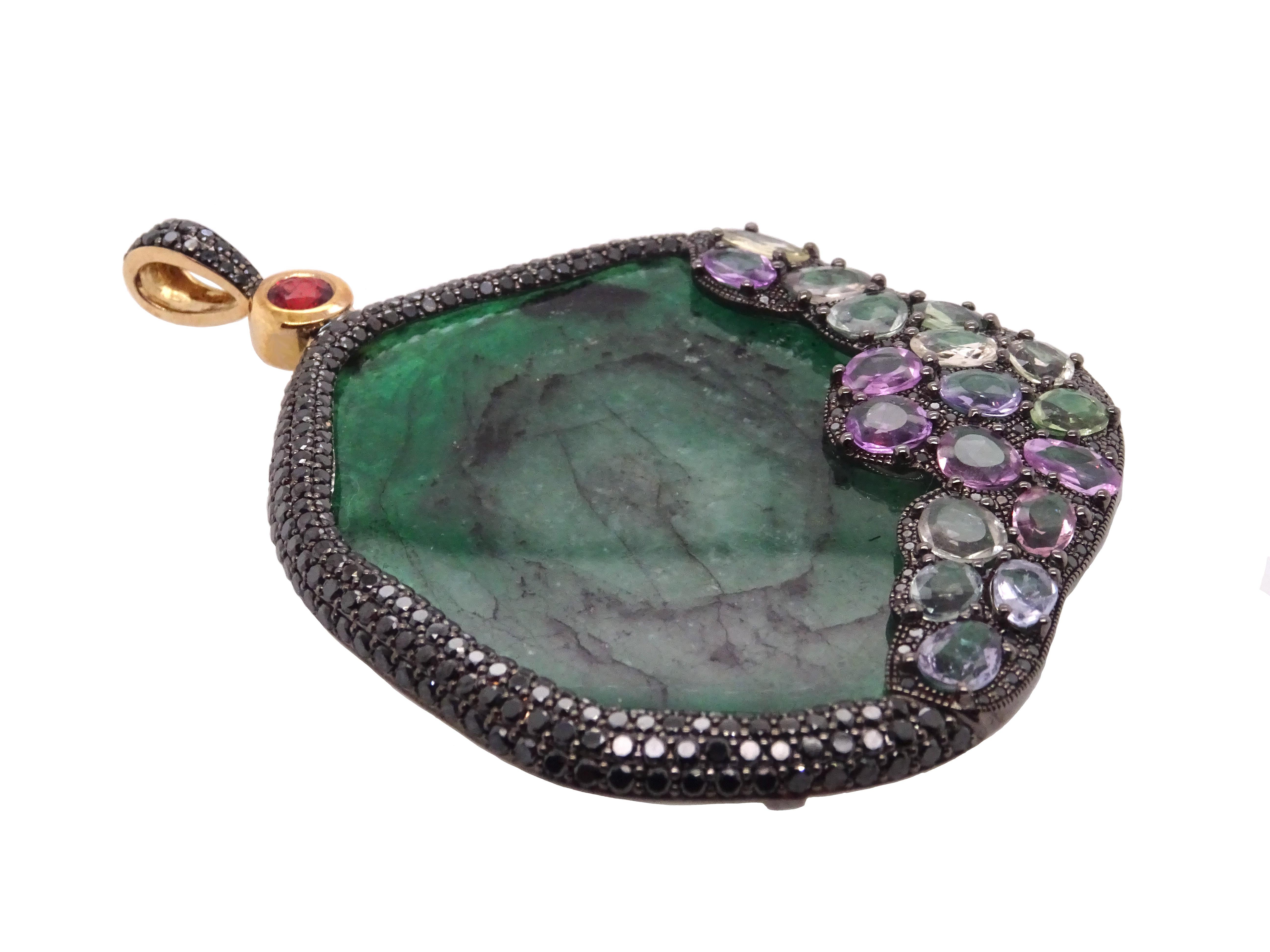 Pure Venom collection by VOTIVE.

Indulge in the captivating allure of this pendant, featuring an exquisite combination of emerald, black diamonds, and red & multicolored sapphires, set in 18K yellow gold. The distinctive center emerald is