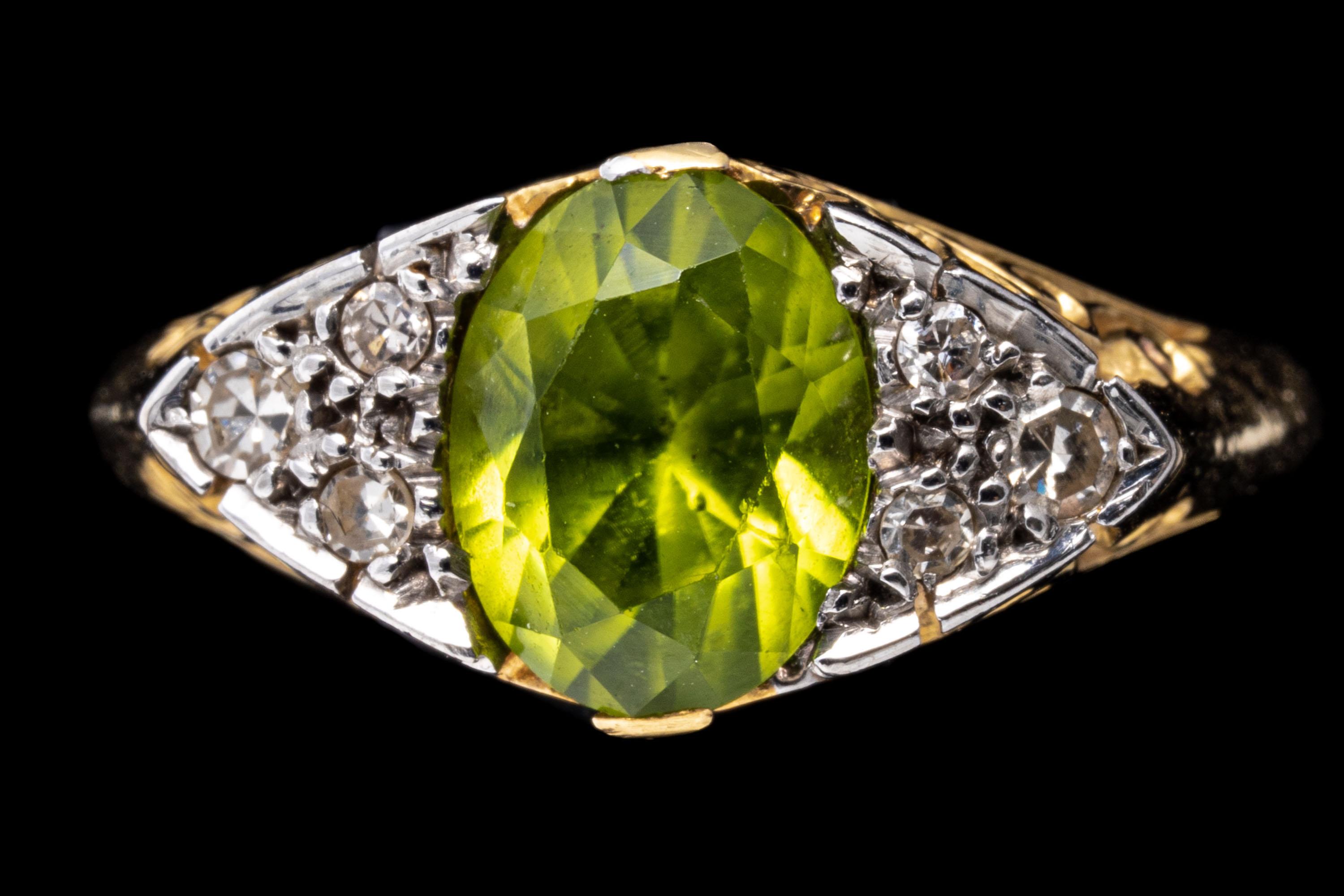 18k yellow gold ring. This classic yellow gold ring has an oval faceted, green peridot center, approximately 1.39 CTS and flanked by a cluster of three round faceted diamonds, approximately 0.06 TCW, prong set, and finished by a scroll work