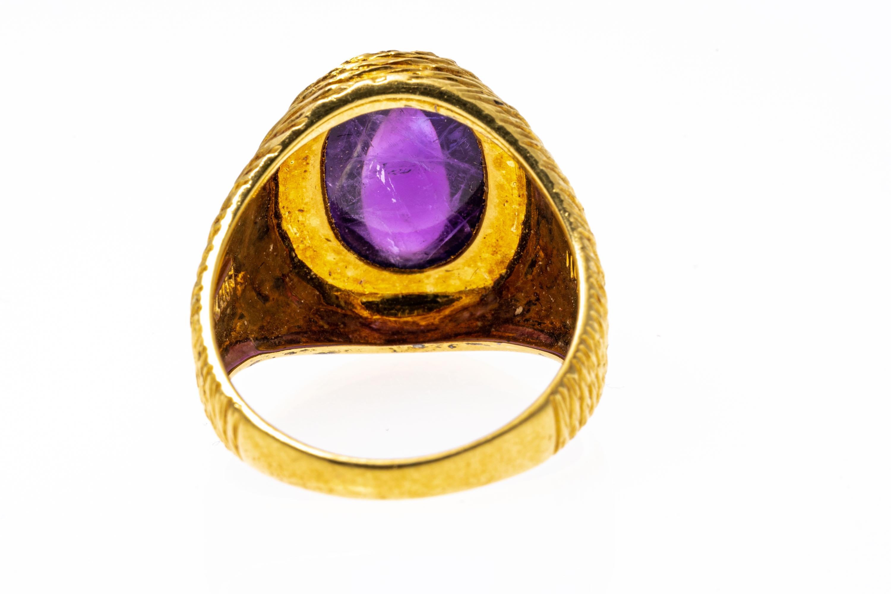 18k yellow gold ring. This handsome ring features an oval, dark purple color amethyst cabochon center, approximately 4.2 CTS, bezel set into a wide, fine matte rope patterned setting.
Marks: 18k
Dimensions: 5/16