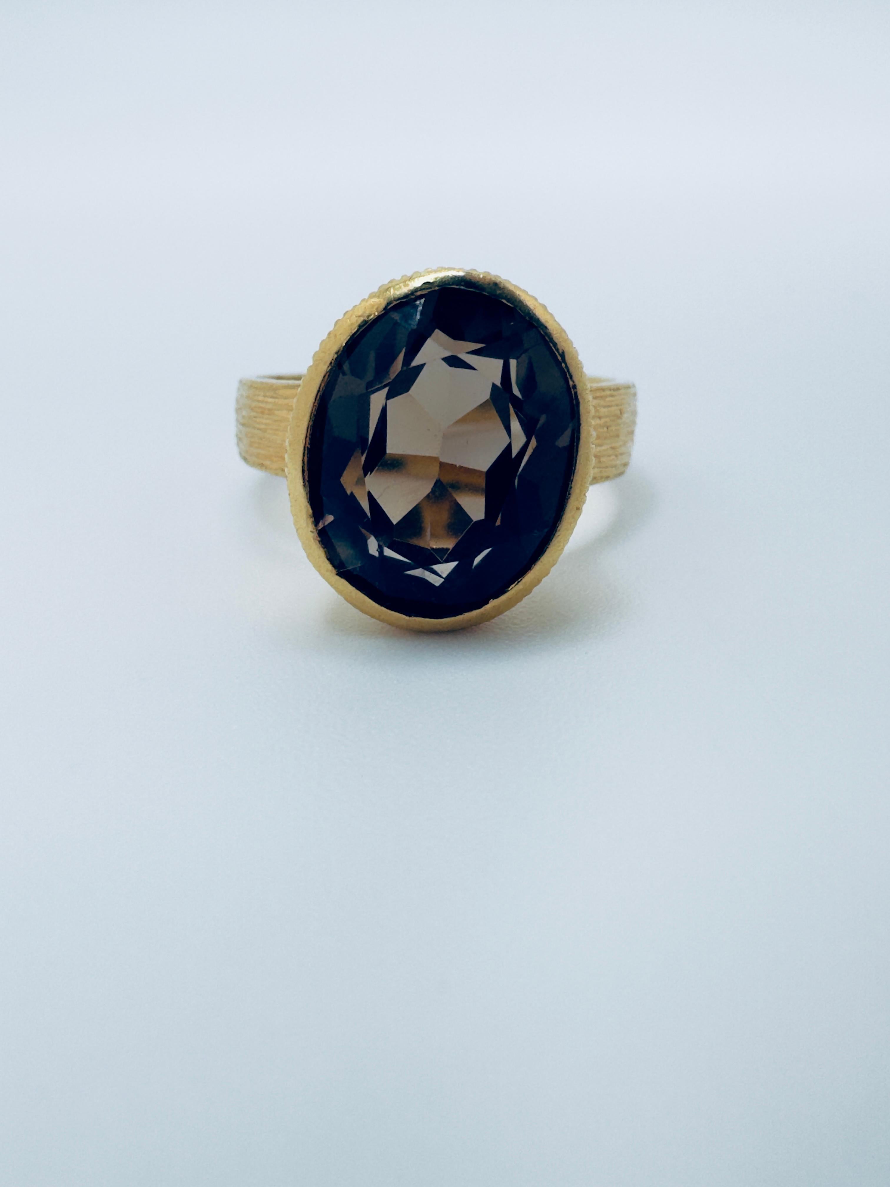 Cette bague exquise est finement réalisée en or jaune 18 carats et met en valeur une captivante topaze fumée ovale en son centre. La pierre précieuse à facettes mesure 11,5 x 9,5 x 6,2 mm, pour un poids total de 3,62 carats, et présente une riche