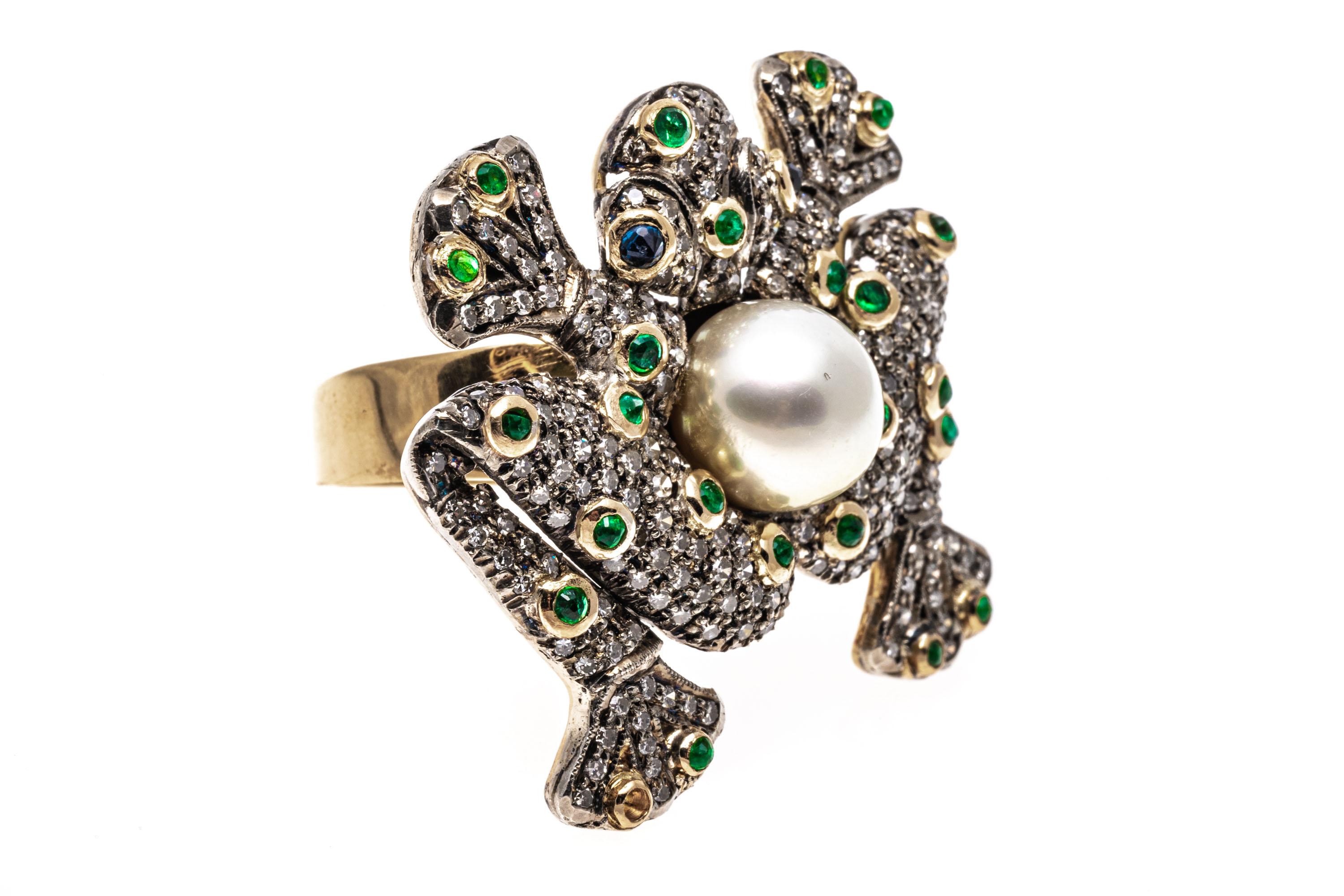 18k yellow gold ring. This striking, impressive ring is a a flat frog, completely pave set with round faceted diamonds, approximately 1.08 TCW and studded with round faceted, green emeralds, approximately 0.59 TCW, bezel set, and decorated in the