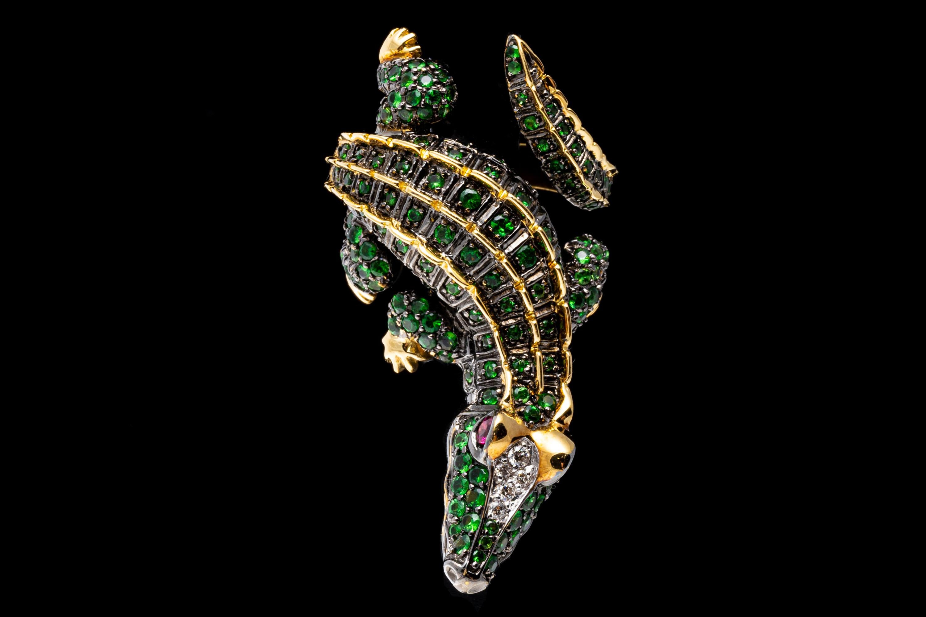 18k yellow gold ring. This stunning bypass ring is a figural crocodile, with the head on one side offset from the tail,  pave set with round faceted, green tsavorite garnets, approximately 2.32 TCW and highlighted with round faceted, white diamonds,