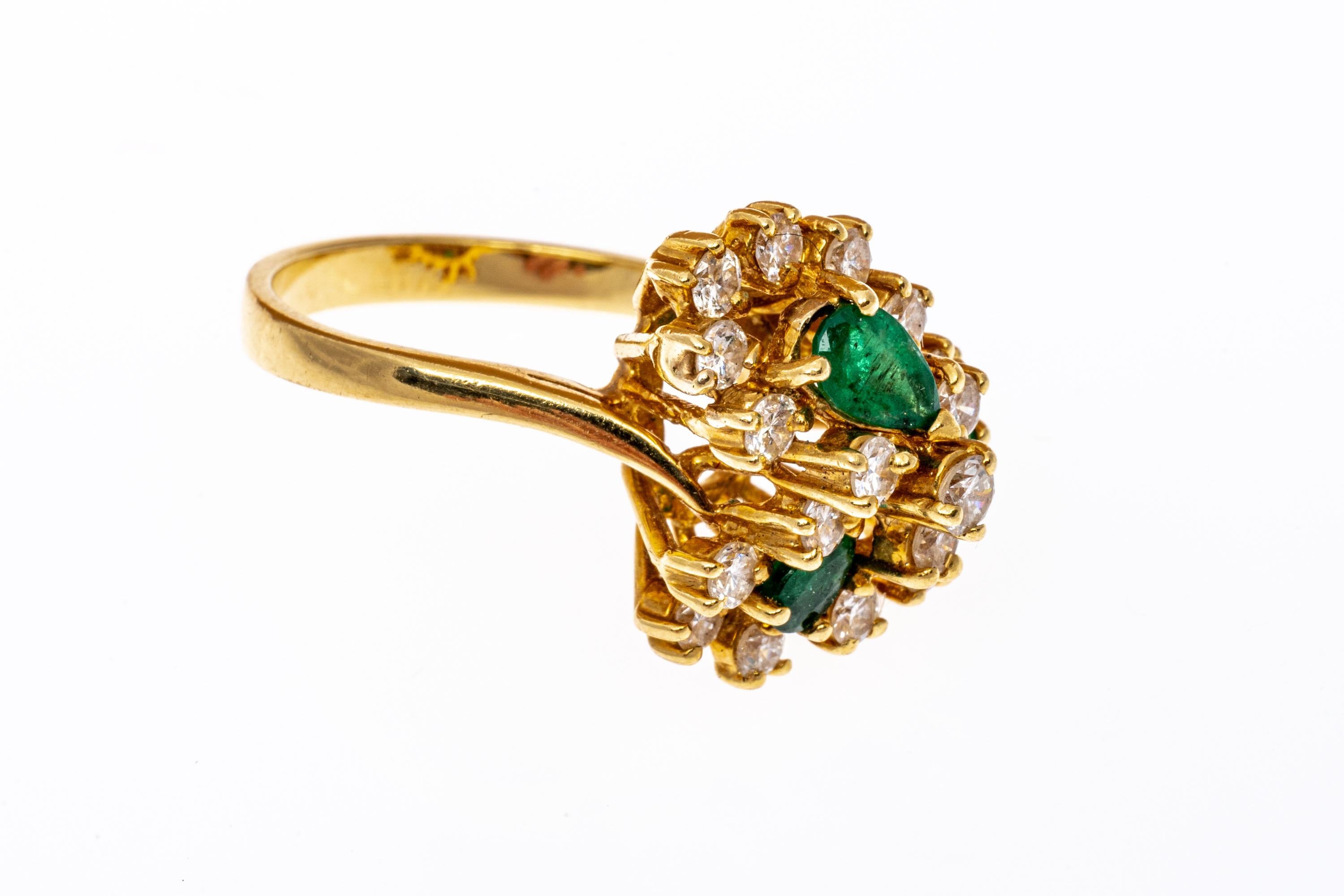18k yellow gold ring. This outstanding ring contains three pear shaped faceted round, deep green color emeralds, prong set, approximately 0.63TCW. Surrounding the emeralds, above and below, are clusters of round brilliant cut faceted diamonds,