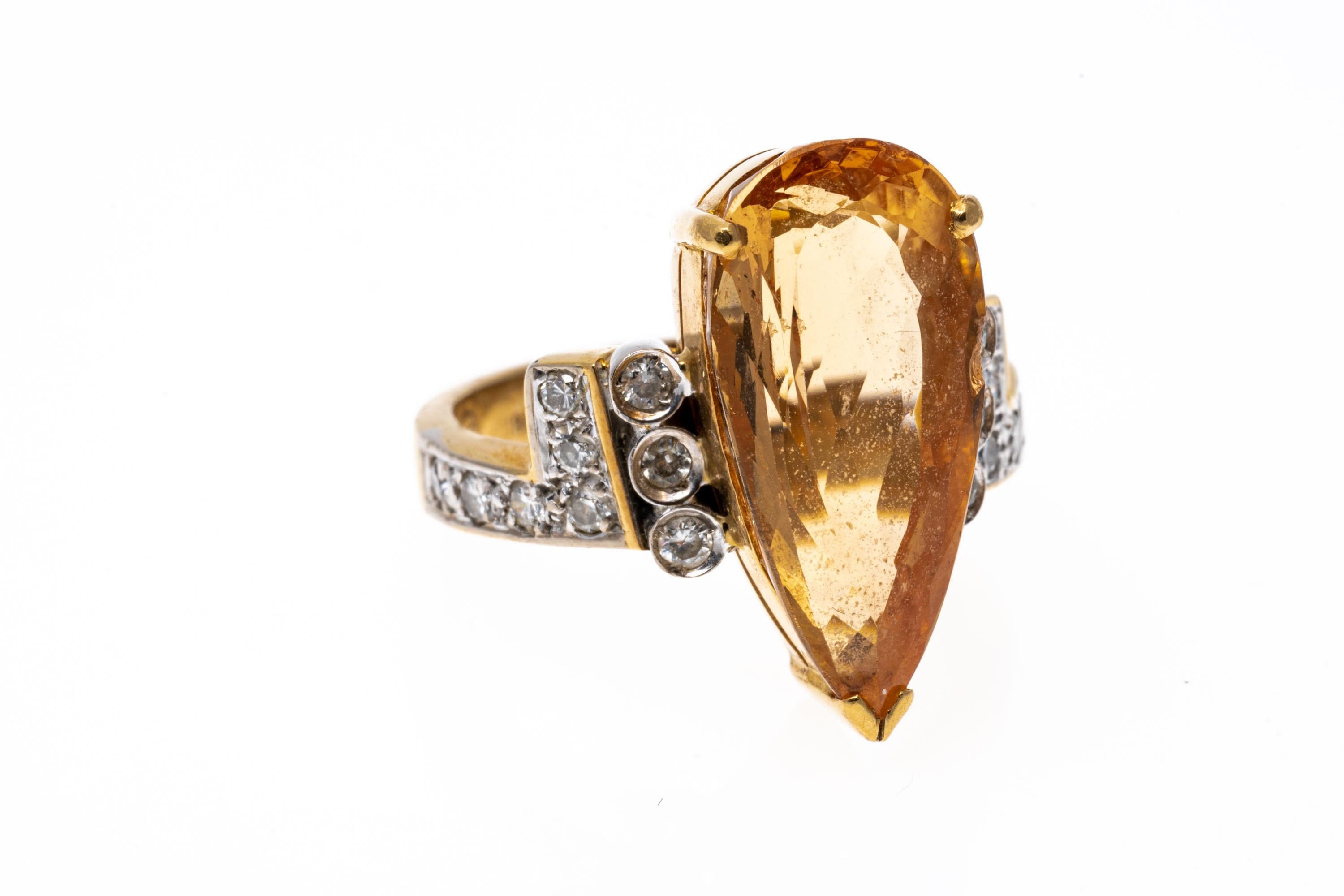 18k yellow gold ring. This gorgeous ring has a center, elongated pear shaped, peach color topaz, approximately 4.81 CTS, and flanked by round faceted diamonds with extend to an 