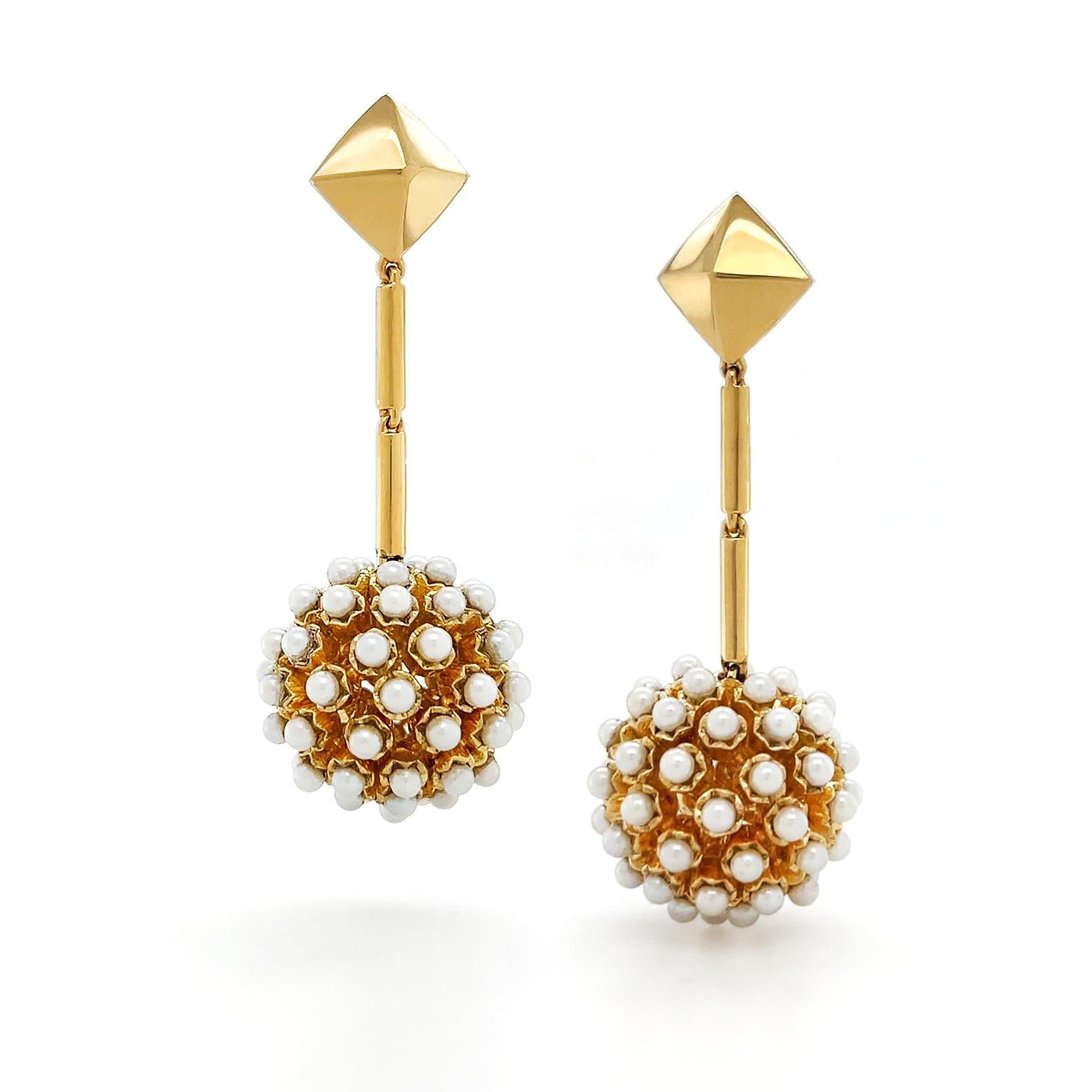 A modern rendition of retro elegance is created with an 18k yellow gold pyramid post that has slim cylinders leading to a dangling ball of round pearls, totaling 122 overall. Friction posts keep the earrings in place. The earrings measure .78 inches