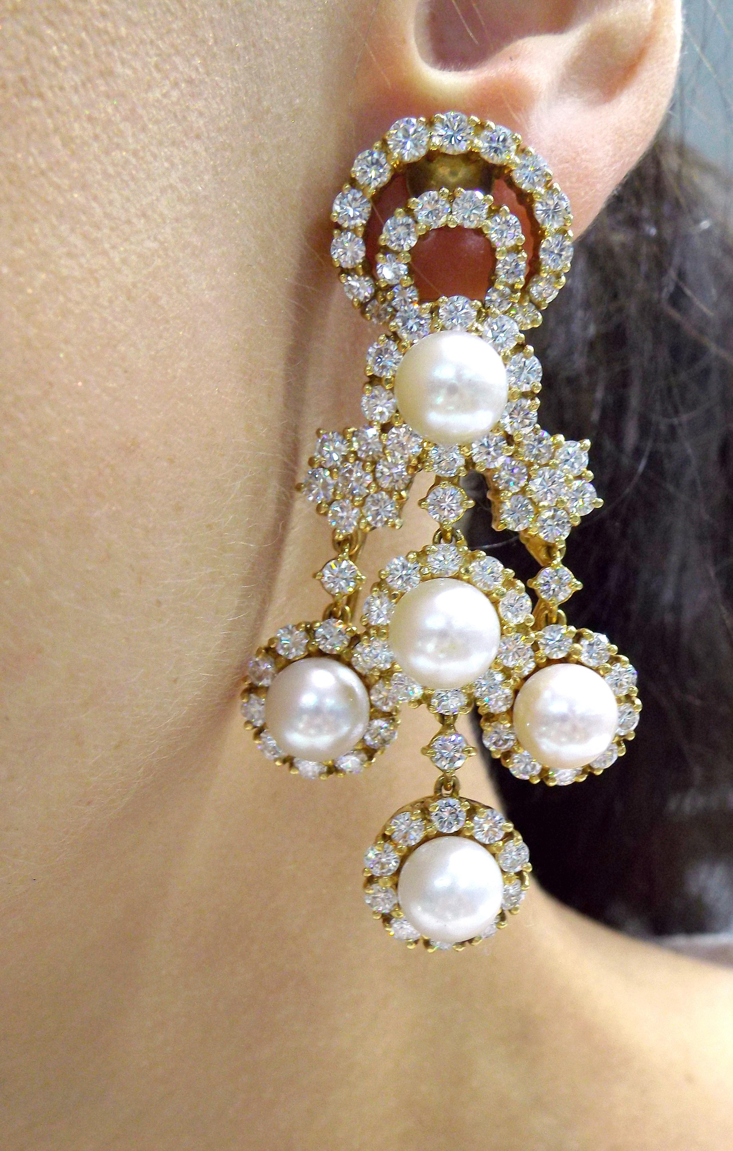 A pair of luxurious chandelier earrings featuring cultured pearls, measuring from approximately 8.50-8.75mm, surrounded by circular-cut diamonds with estimated total diamond weight of 12.00 carats; mounted in 18k gold; length: 2 1/2in.