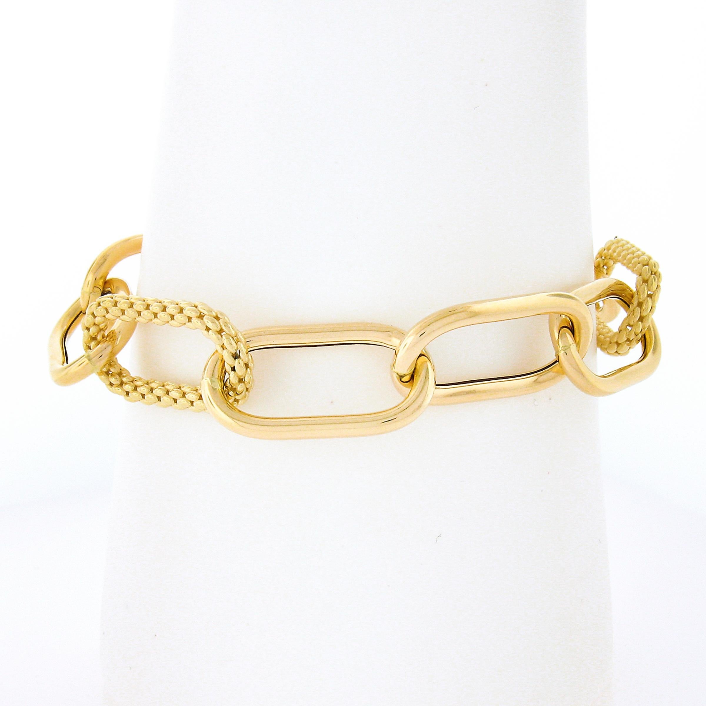This wide and large paperclip link bracelet is crafted in solid 18k yellow and features plain and weave textured links that hollow in design which gives makes the bracelet its large and big show. It is secured with an oversized spring ring clasp
