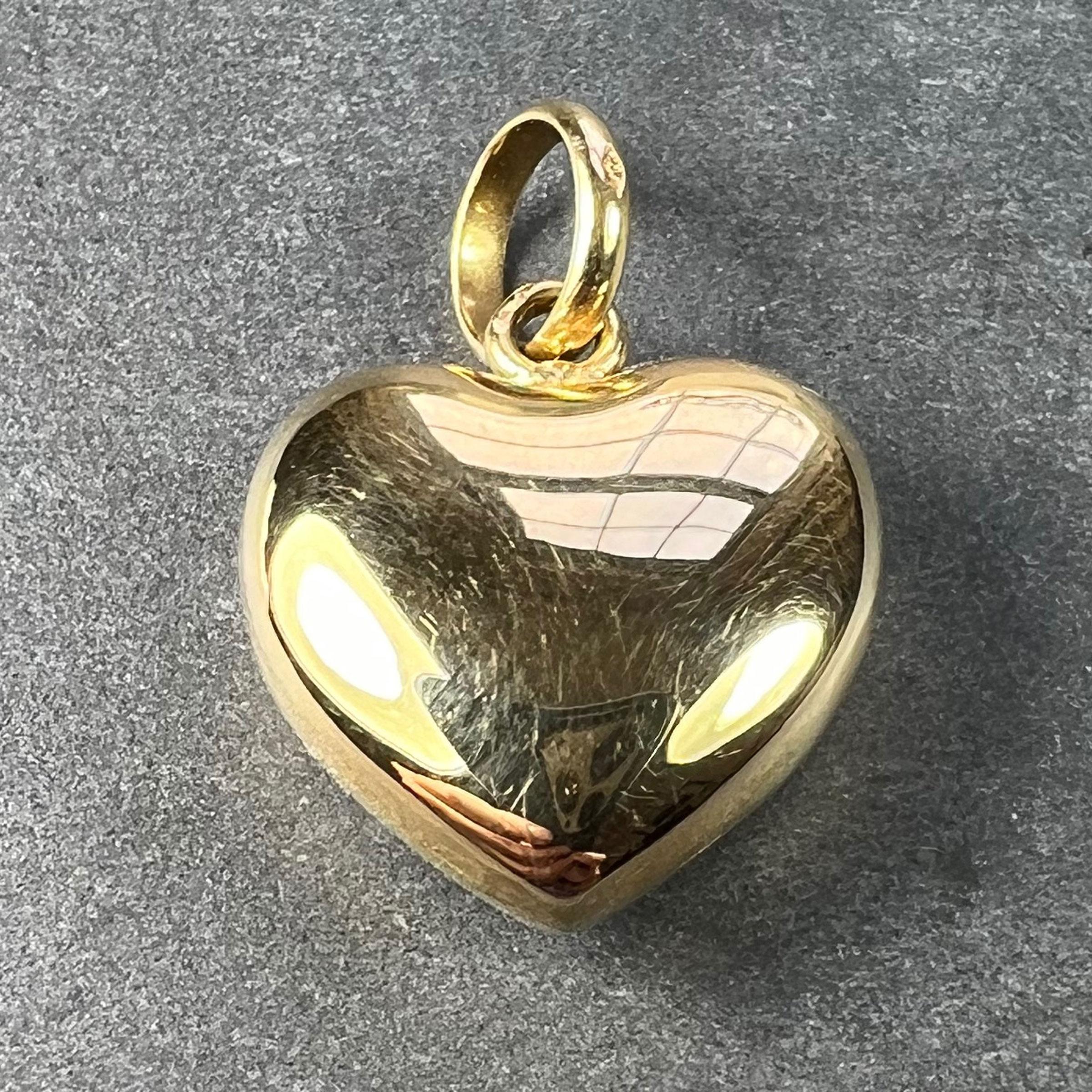 An 18 karat (18K) yellow gold charm pendant designed as a puffy love heart, with a brushed satin finish to one side, and the other polished to a shine. Stamped 750 for 18 karat gold to the inside of the pendant bail, with French import