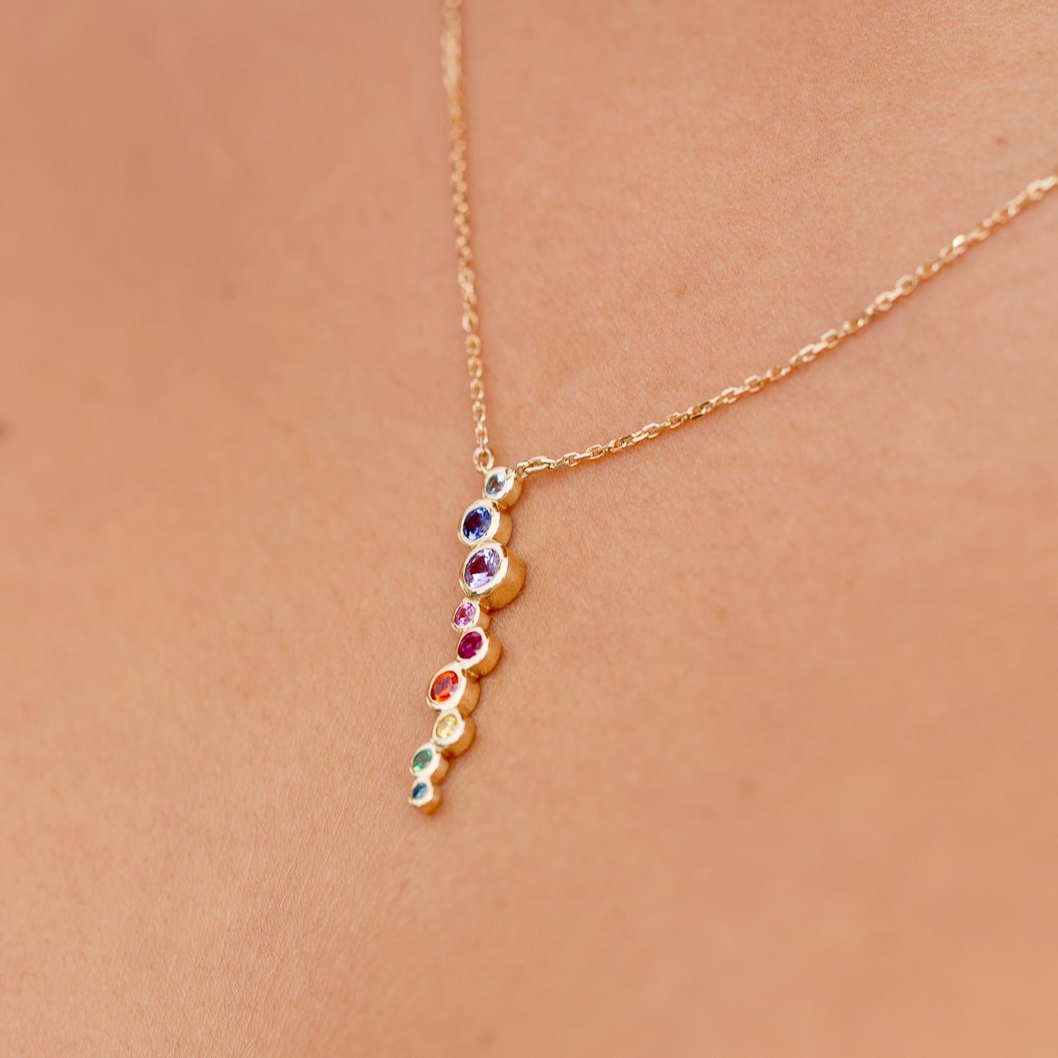 Dieser elegante Cascade-Anhänger wurde in luxuriöser Handarbeit aus strahlendem 18-karätigem Gelbgold gefertigt und zeigt einen zarten Wasserfall aus regenbogenfarbenen Steinen. Angefangen beim Aquamarin, über verschiedene Farben von Saphiren,