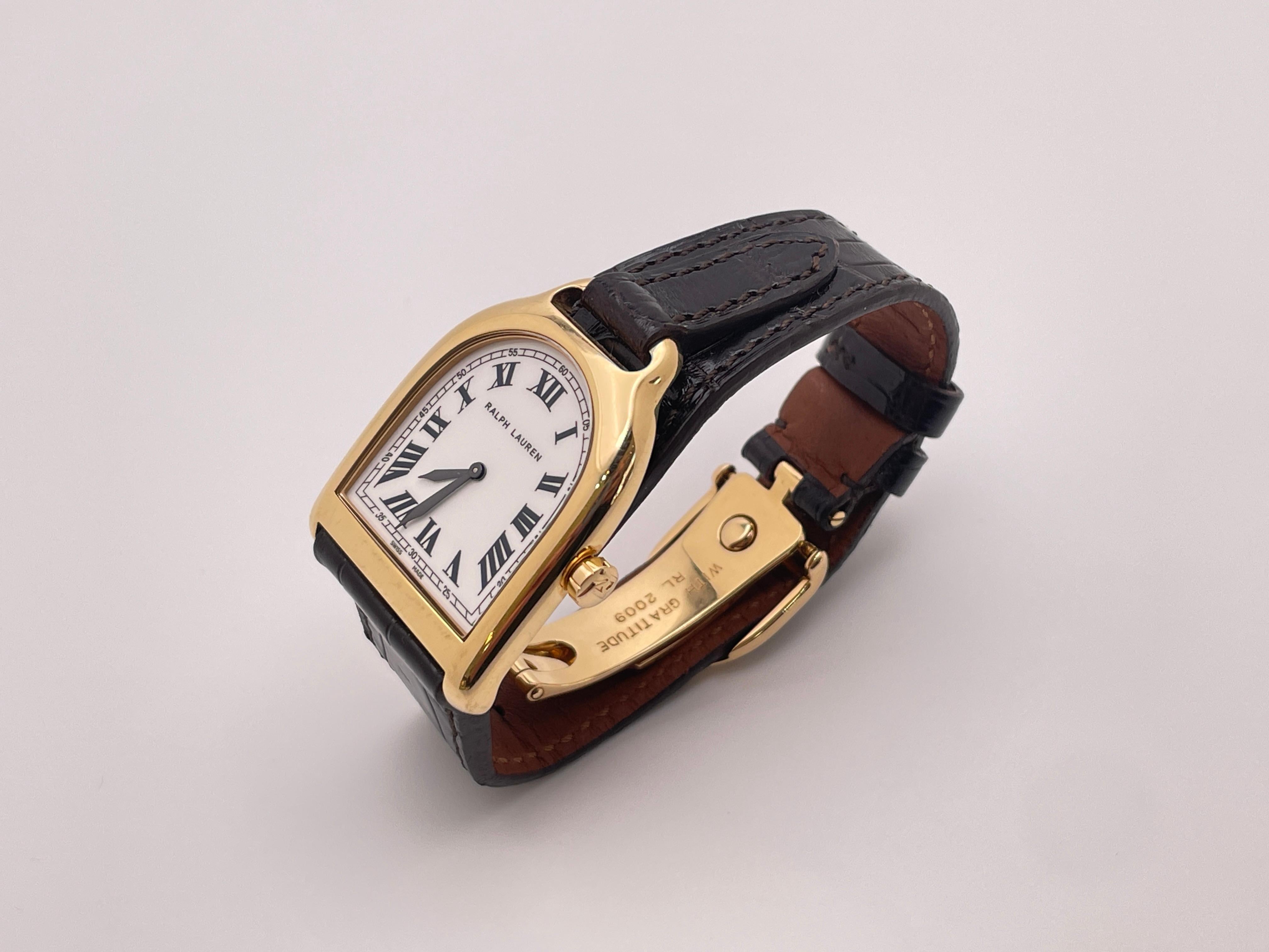 A unique 18K yellow gold Ralph Lauren Stirrup watch. This beautiful RL watch is crafted with a yellow gold case and a refined black alligator strap featuring an exquisite stirrup-inspired closure and an 18K yellow gold folding buckle. It features a