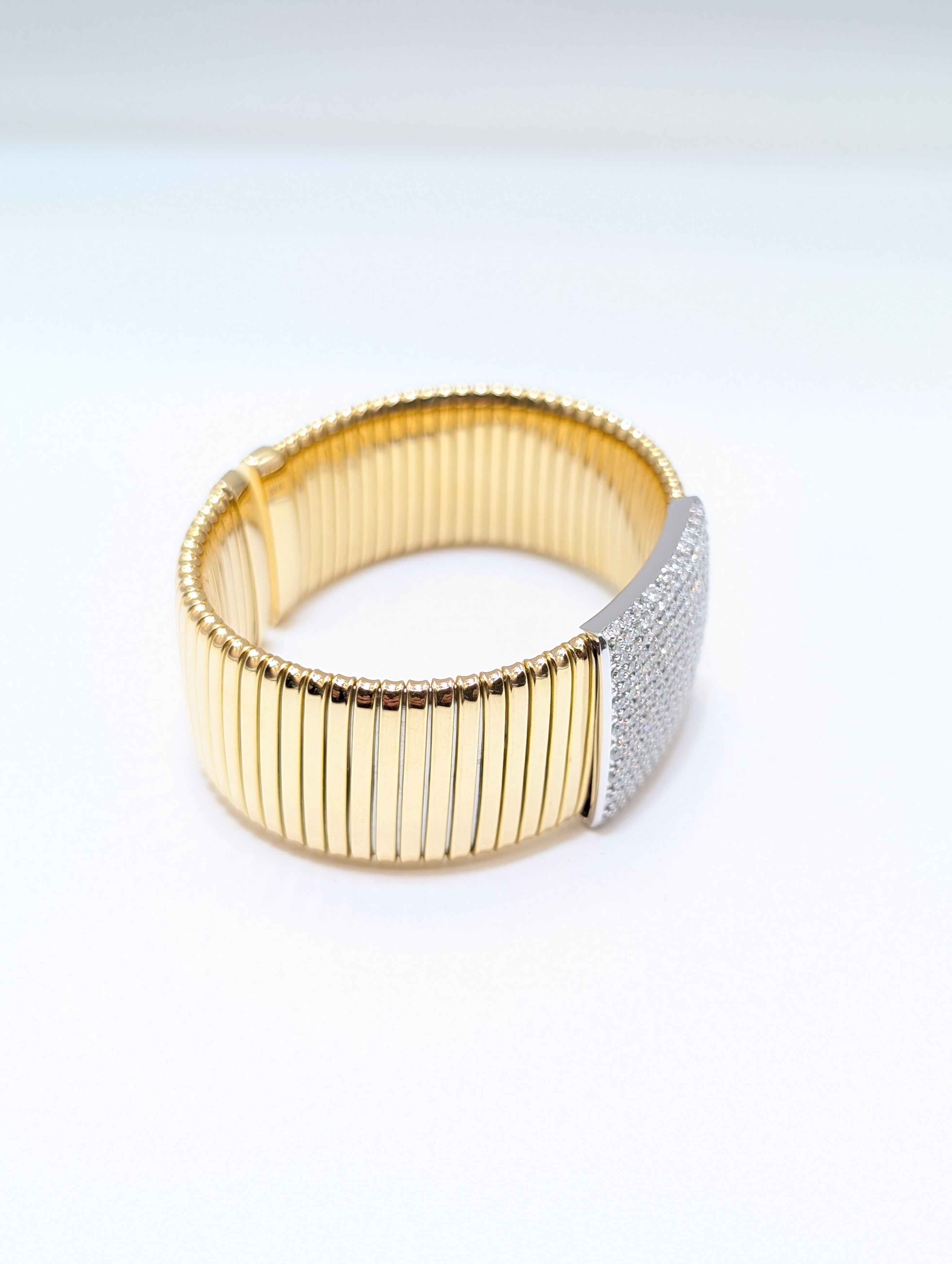 Ce bracelet à larges côtes en or jaune 18 carats est une véritable pièce de luxe et d'élégance qui attire l'attention. Pesant plus de 39 grammes d'or riche, cette manchette audacieuse est ornée de 5,21 carats de diamants ronds de taille brillant,