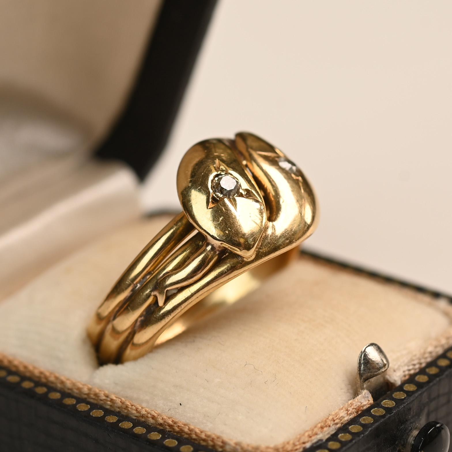 A rare English Victorian era band, circa 1890s, featuring an exquisite double-head snake motif. Each head is set with a prong-set diamond, with a combined weight of approximately 0.10 carat. The band is designed with a distinctive triple-wire shank