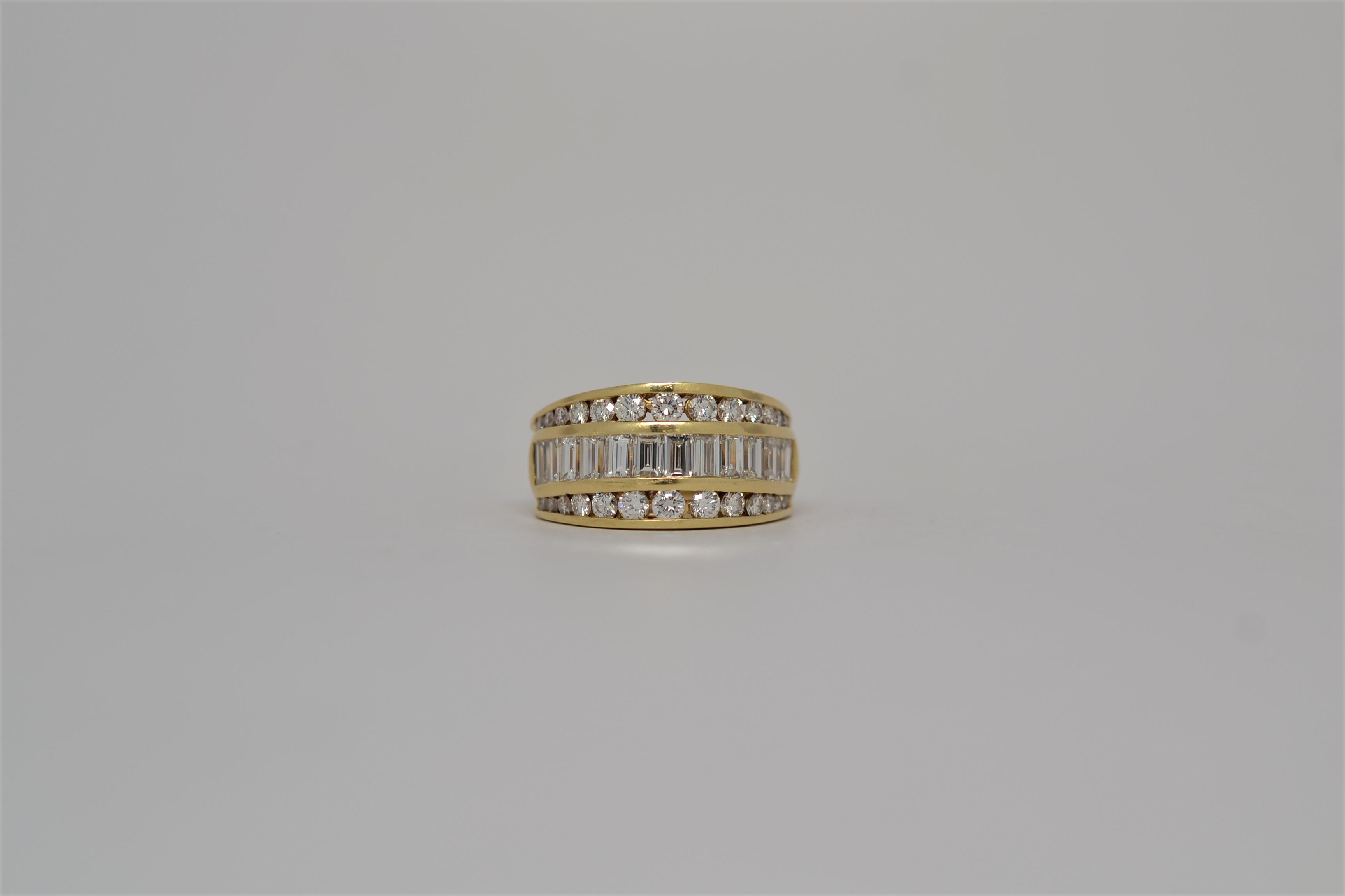 Ein Ring aus 18 Karat Gelbgold in dreireihiger Anordnung, besetzt mit Diamanten im Baguette- und Rundbrillantschliff. Die Diamanten sind in handgefertigte Kanäle gefasst, die den Ring zur Hälfte umschließen. Der Ring verjüngt sich von 11,5 mm auf