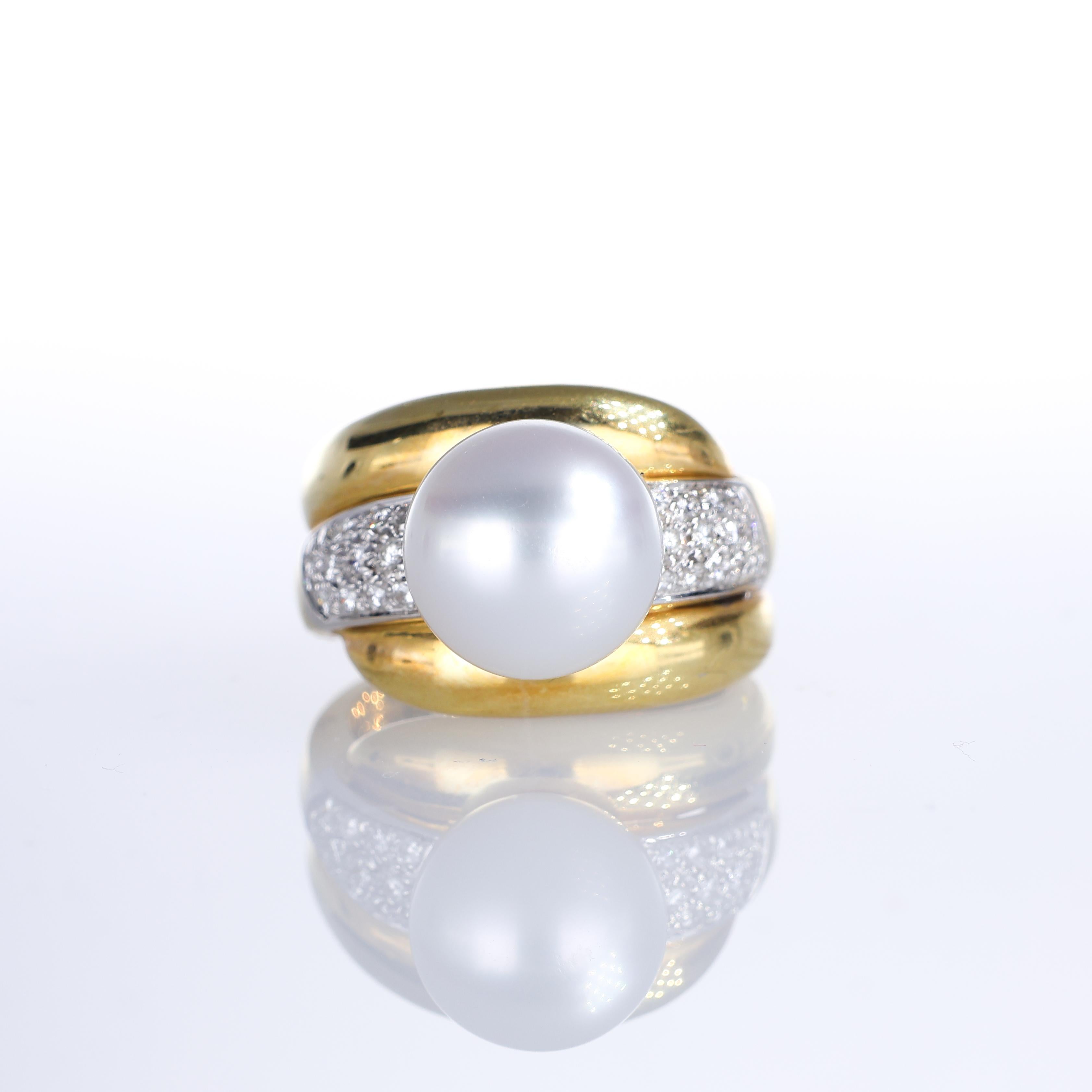 A bold 18K yellow gold ring featuring a 10mm central pearl, framed by two rows of brilliant-cut diamond pavé totaling 0.60 carats. The sculptural gold setting enhances the pearl’s natural luster, creating a refined statement piece with a timeless