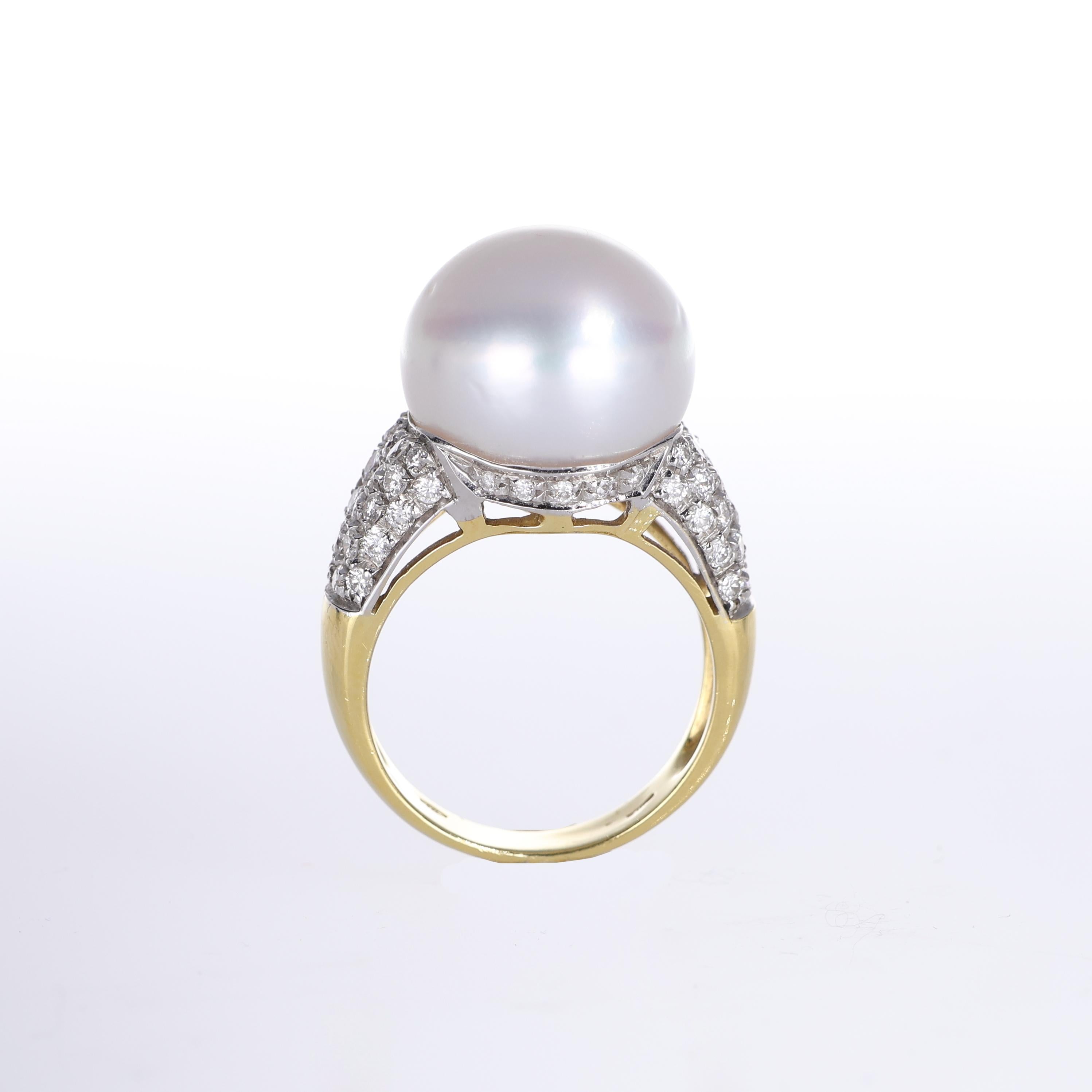 An elegant 18k yellow gold ring featuring a striking 15mm white pearl as its centerpiece. The sophisticated design is enhanced by pavé-set brilliant-cut diamonds adorning the sides, adding brilliance and refinement. A timeless statement piece that