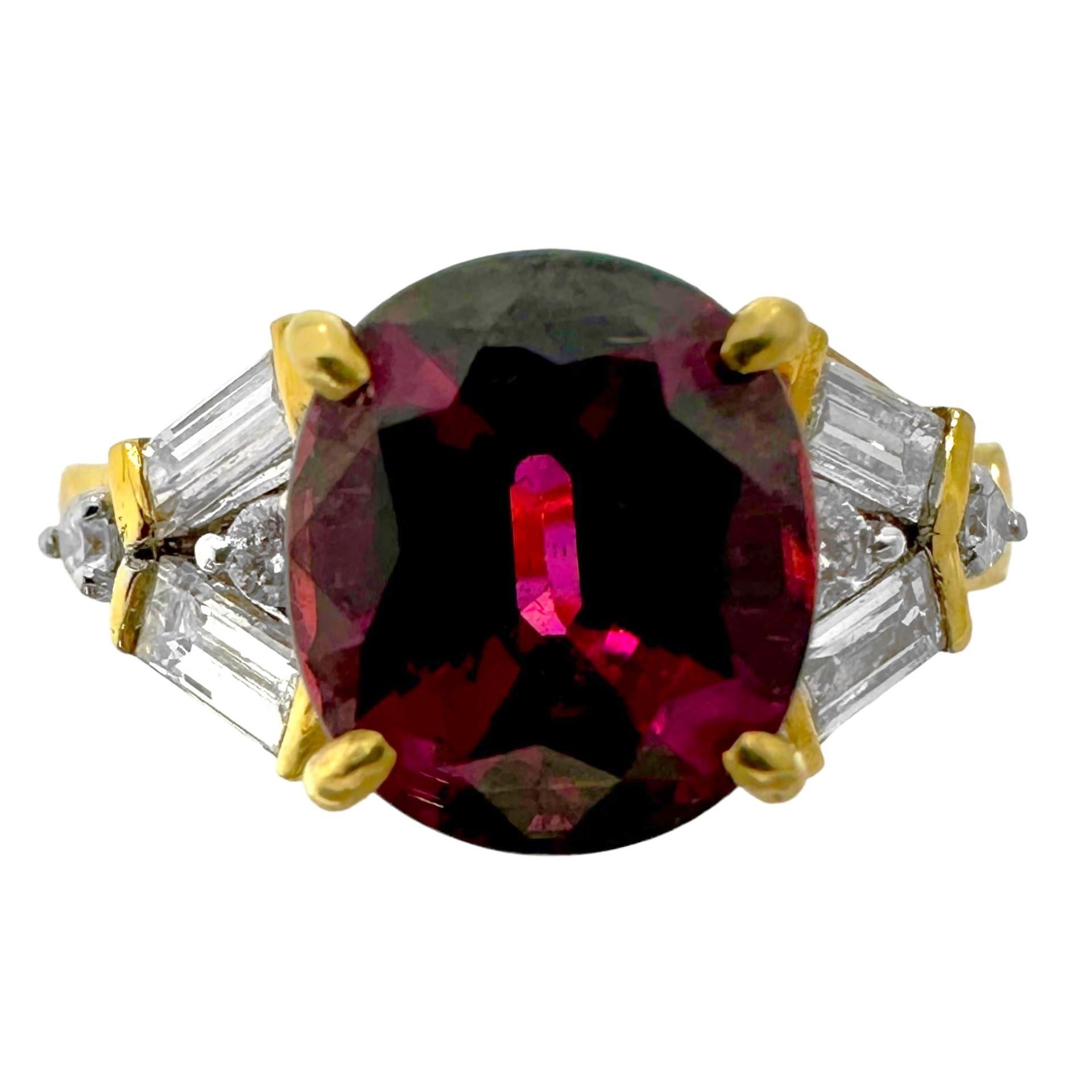 This traditional 18k yellow gold solitaire ring is a bit out of the ordinary. A sumptuous Rhodolite Garnet, exhibiting all the colors of fine red wine, is set at the center and is flanked by a total of four straight baguette and four brilliant cut