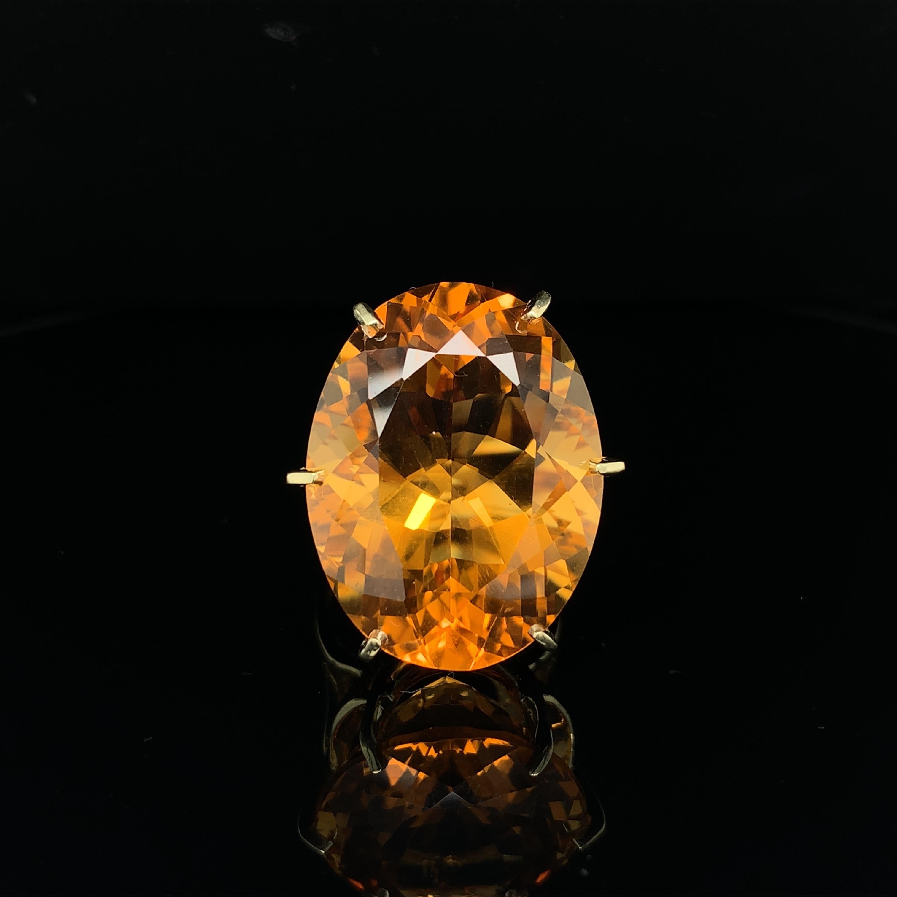 18K yellow gold ring featuring a large oval citrine weighing 37.31 carats. The citrine is freshly polished and has extra faceting. It has a golden orange-yellow color. The citrine measures about 26mm x 20mm. The ring fits a size 8.75 finger and is