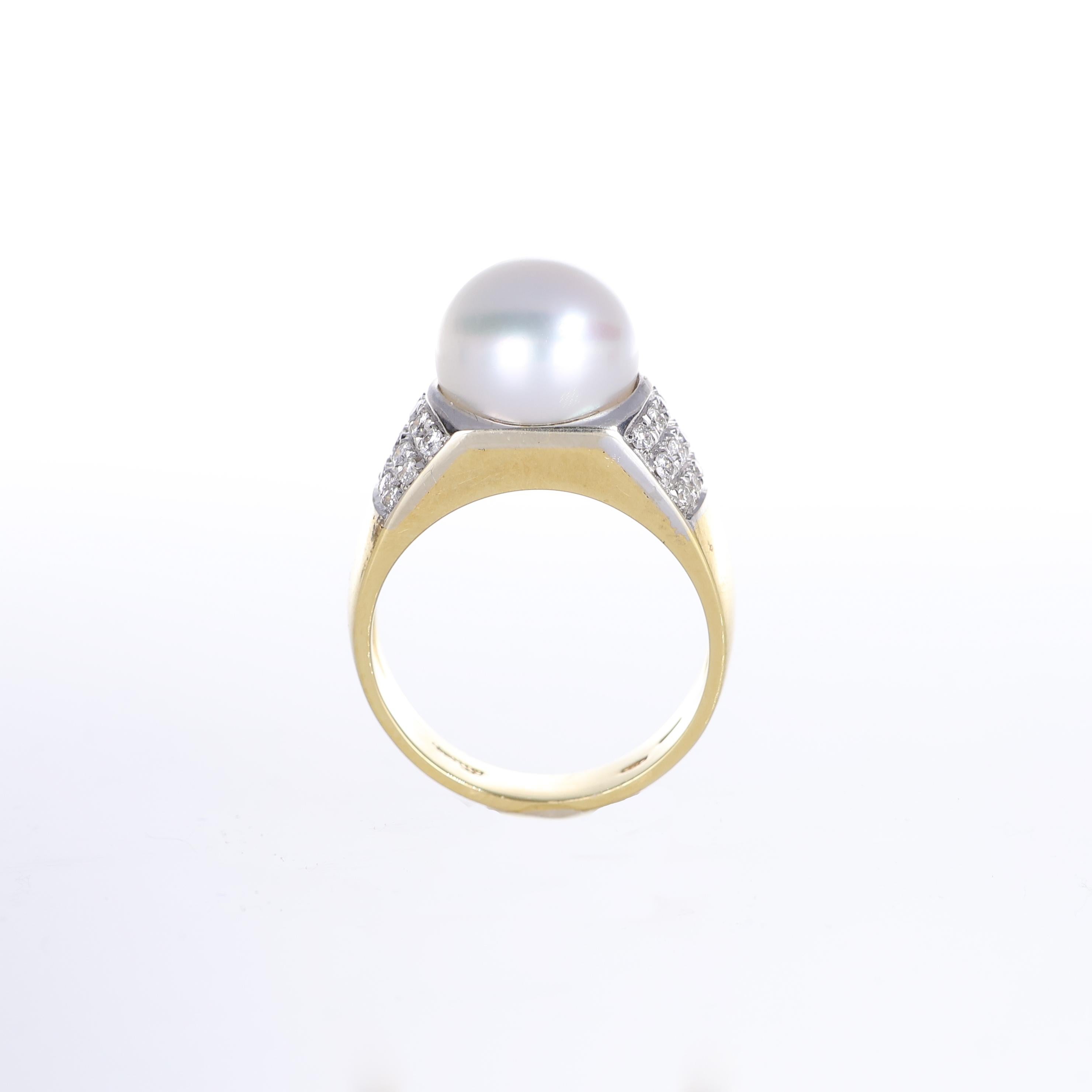 A refined 18K yellow gold ring featuring a luminous 9mm pearl at its center, framed by pavé-set natural diamonds on both sides. The clean, structured design enhances the elegance of the pearl while the diamond pavé adds a touch of brilliance, making