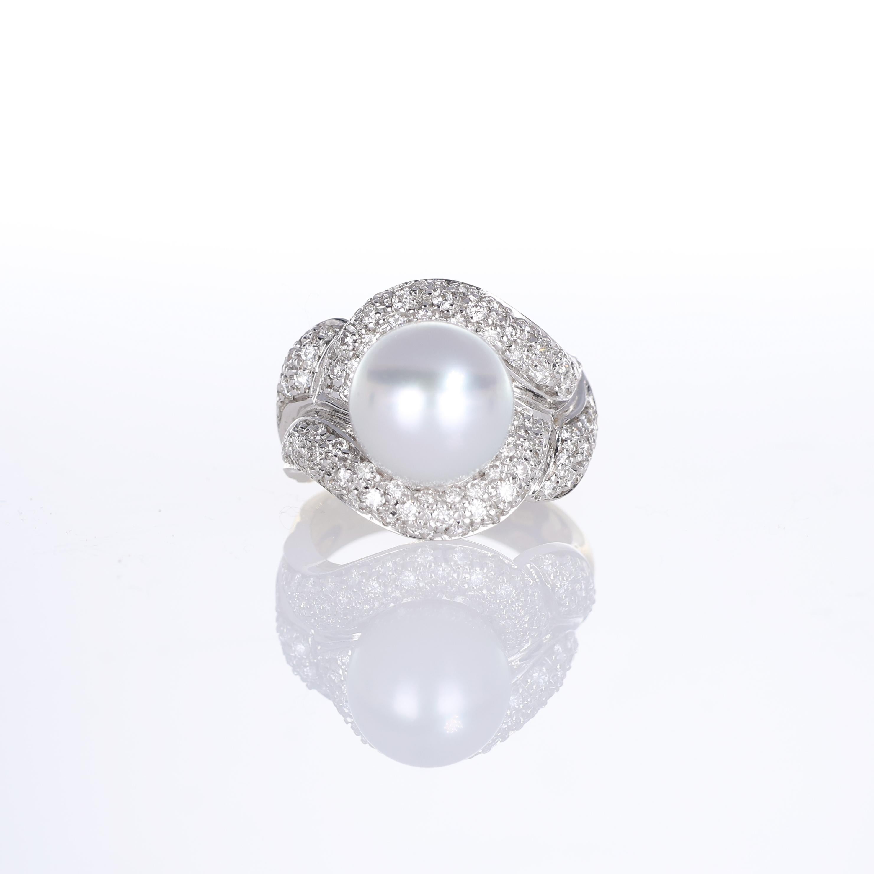 An elegant 18K yellow gold ring featuring a luminous central pearl, embraced by an intricate white gold weave adorned with pavé-set natural diamonds. The contrast between the two gold tones and the brilliance of the diamonds enhances the sculptural