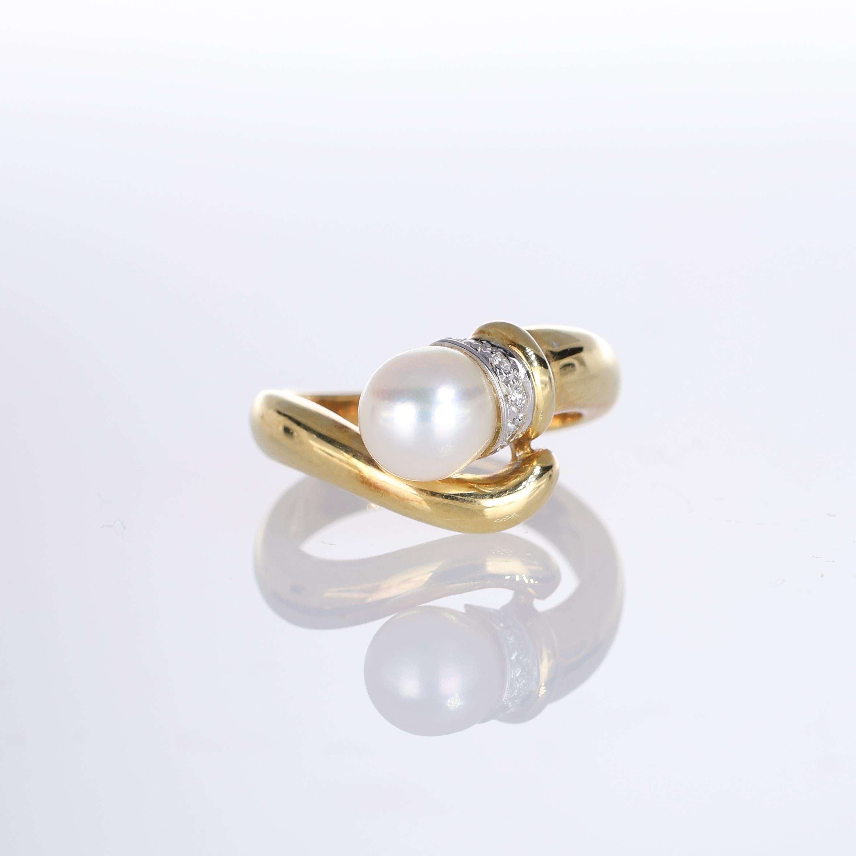 A refined 18k yellow gold ring featuring a 5mm lustrous central pearl, elegantly cradled in a bezel adorned with 0.40 carats of brilliant-cut diamonds. The fluid, sculptural design adds a contemporary touch to this classic combination of pearl and