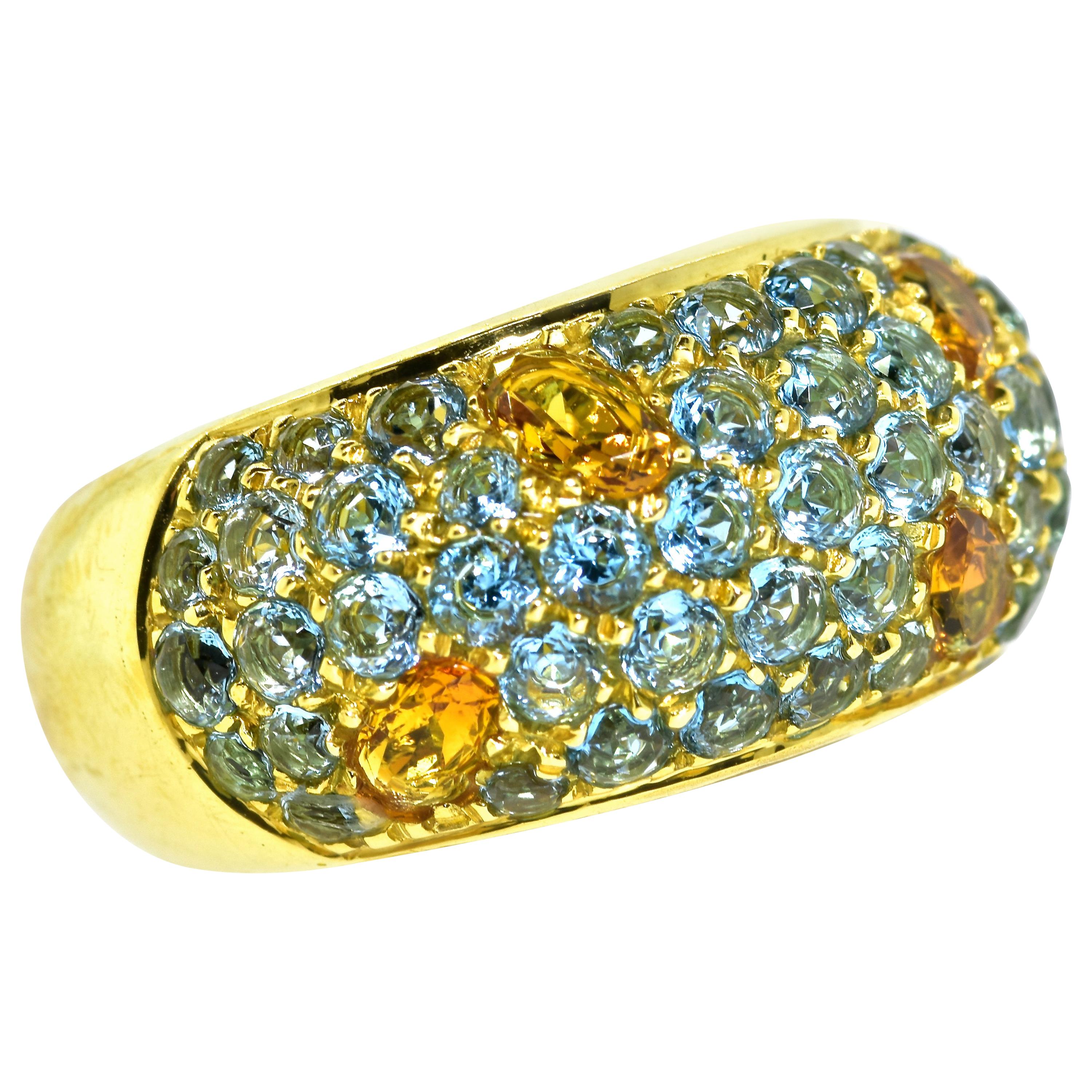 18K yellow gold band measuring 12.21 mm. wide possesses 4 fine oval cut deep orange natural citrine, weighing an estimated 1.5 cts., and  set within a bed of 50 round natural round brilliant cut blue topaz weighing and estimated 4.5 cts.  All of the