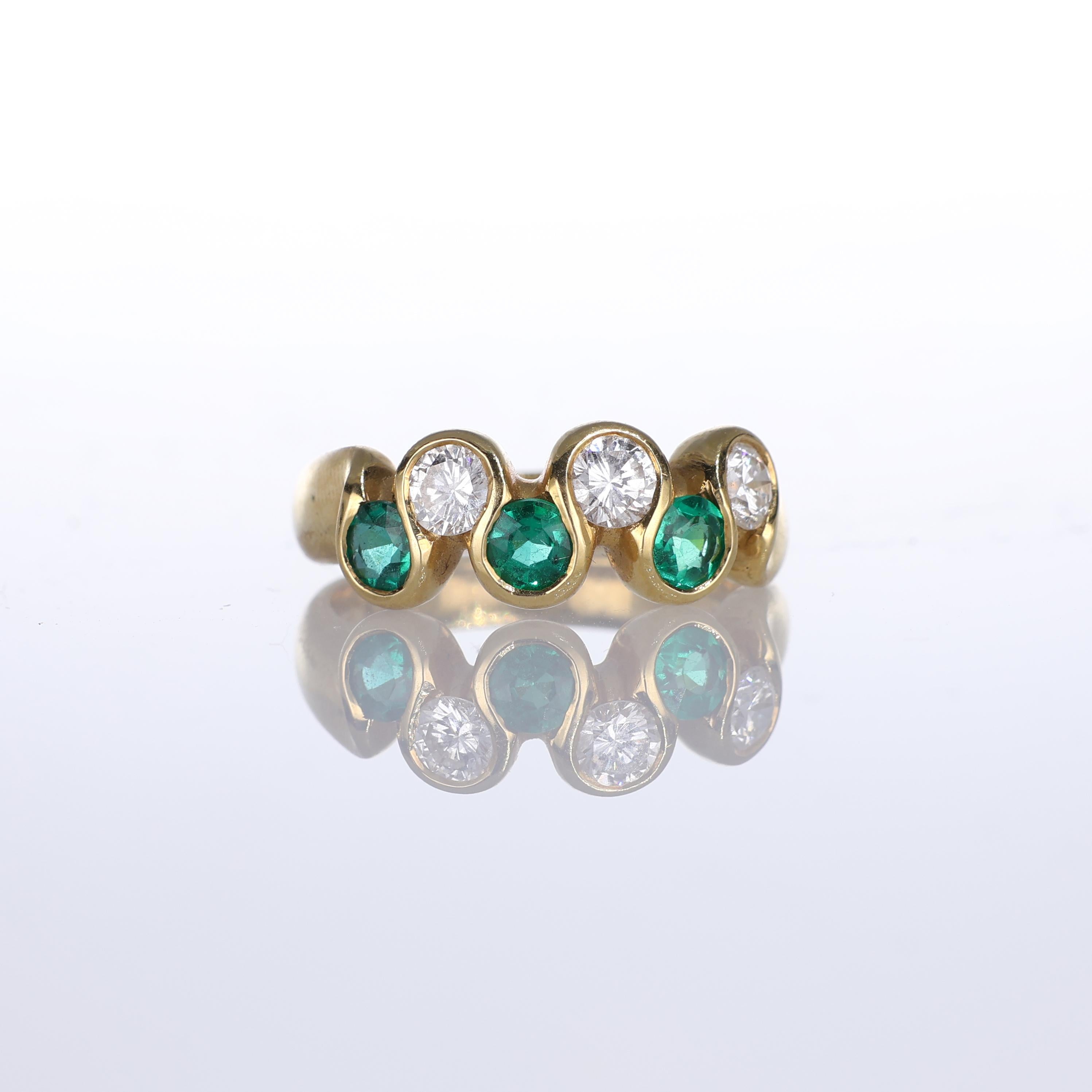 A sophisticated 18k yellow gold ring featuring a harmonious arrangement of three vibrant round-cut emeralds, totaling 0.58 carats, alternating with three brilliant-cut diamonds, totaling 0.63 carats. This balanced design combines color and