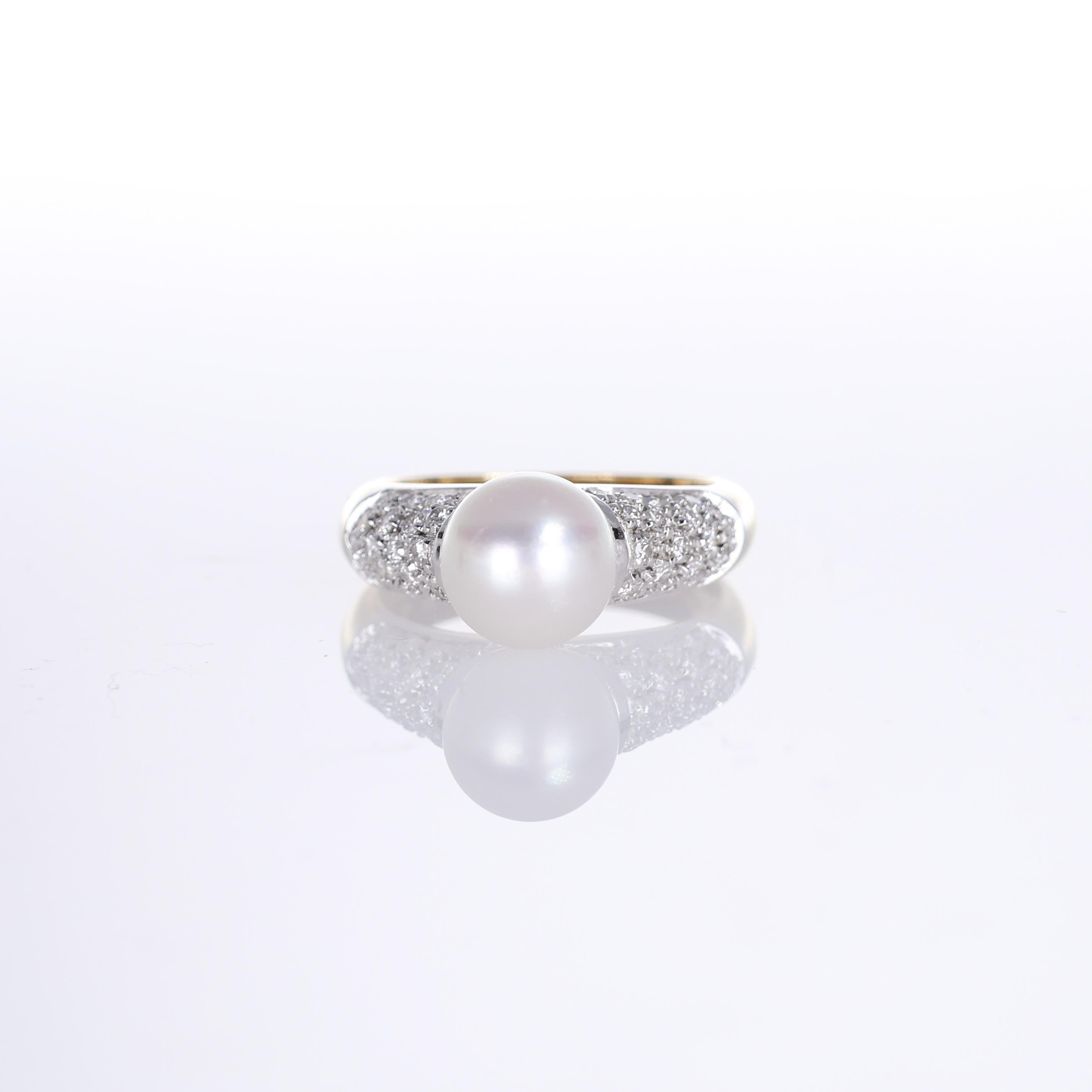 A refined 18K yellow gold ring featuring a luminous 8mm white pearl as its focal point. The elegant band is adorned with pavé-set natural white diamonds on either side, enhancing the pearl's radiance. A sophisticated piece that blends timeless charm