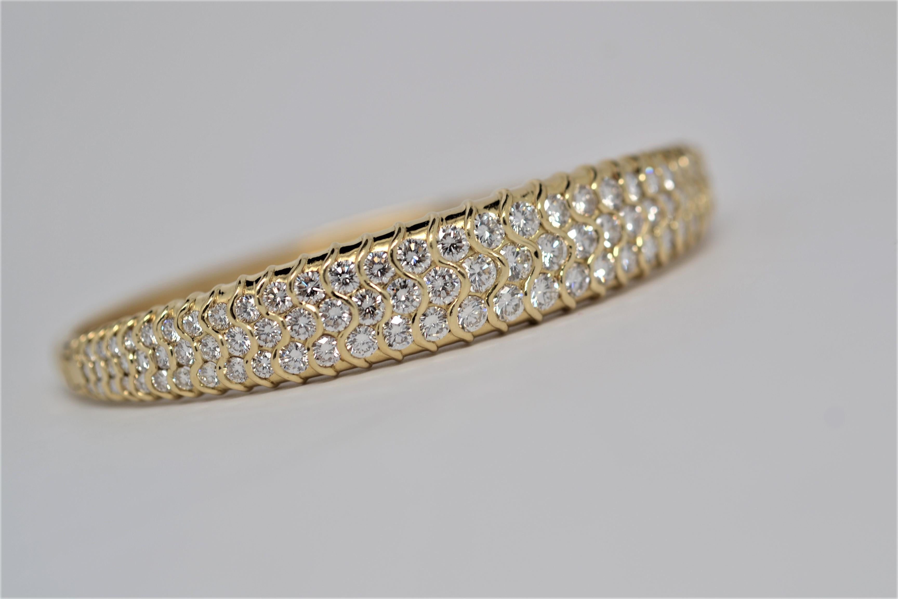 An elegant 18K Yellow Gold and Diamond bangle bracelet. This handmade bangle is 18K Yellow Gold and set halfway around with Round Brilliant Cut Diamonds in a graduated layout. A total of ninety nine Round Brilliant Cut Diamonds weighs 5.54ct,