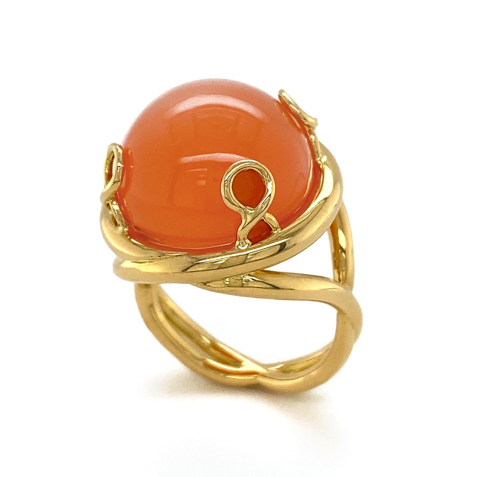 Gold elevates a rare shade of moonstone in this ring. The gem known for its shimmering effect, is featured in the variation of orange. 18k yellow gold whirls into prongs to hold the cabochon. Revolving around the gem is a thick strand of gold that