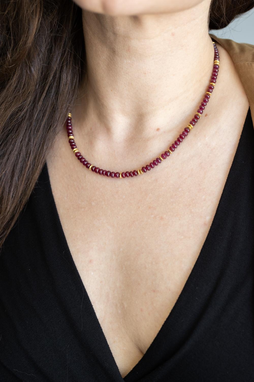 Ce luxueux collier présente des perles de rubis lisses d'un poids total en carats de 110,89ctw. Cette pièce élégante est ornée de petites entretoises en forme de lentilles et d'un fermoir à bascule ondulé, le tout réalisé en or jaune 18k. D'une