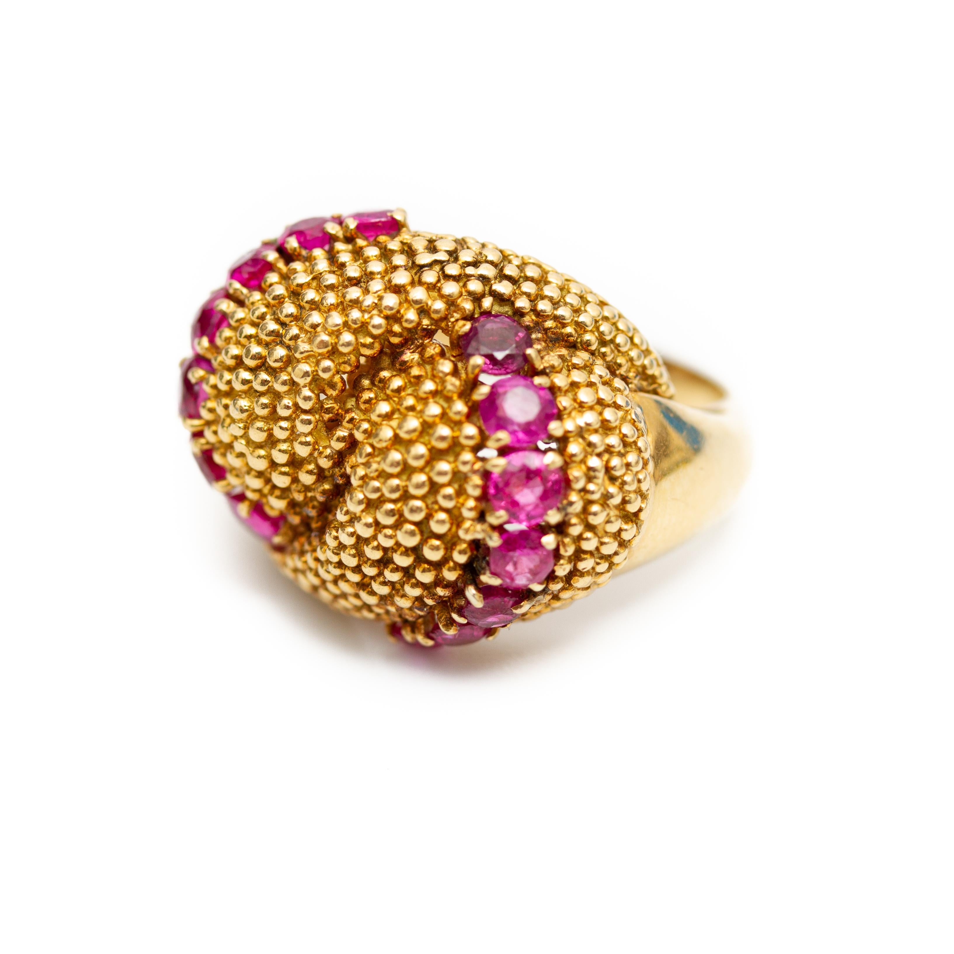 Offered is an 18K yellow gold ruby domed ring made in Italy. This oblong domed ring features curved rows of round rubies amid a beaded interlocking surface.
