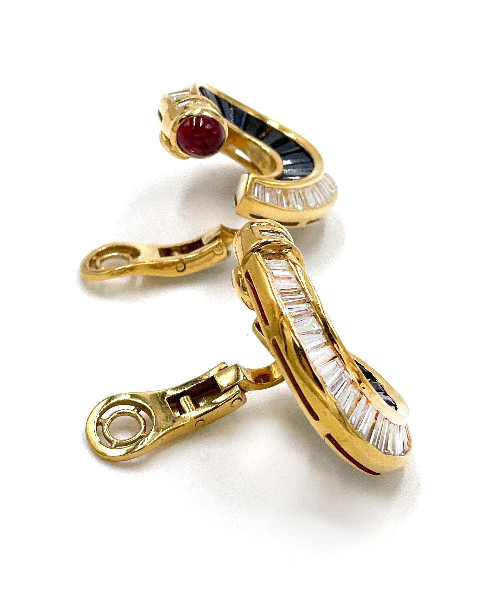 Preowned pair of 18K yellow gold ruby, sapphire and diamond earrings. Each showstopping earring is furnished with onebezel set oval cabochon cut ruby averaging 5.3x4.5mm. The rubies are deep pinkish red color, 5 tone, 5
saturation, VS clarity in a